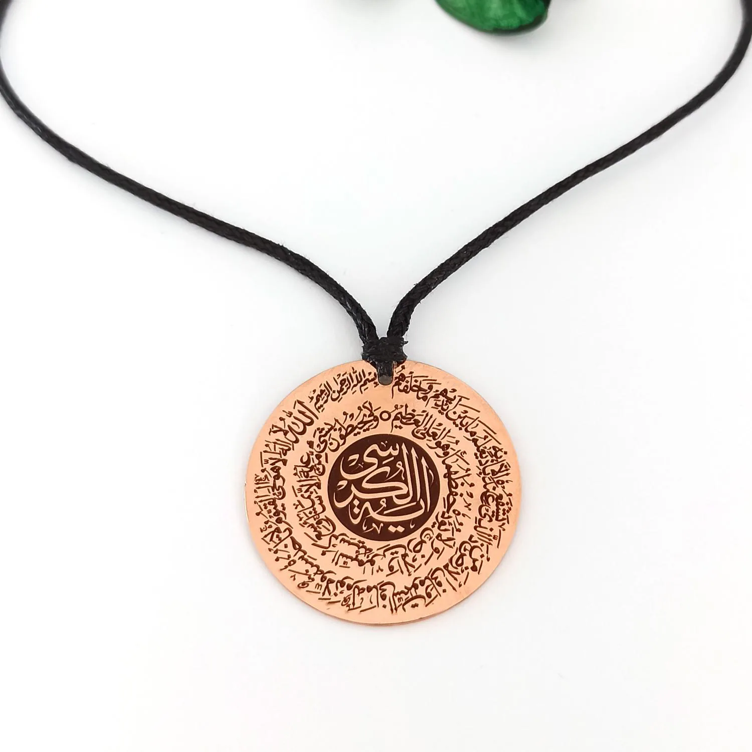 Close-up of Ayatul Kursi engraving on natural copper tone pendant an Islamic jewelry for woman