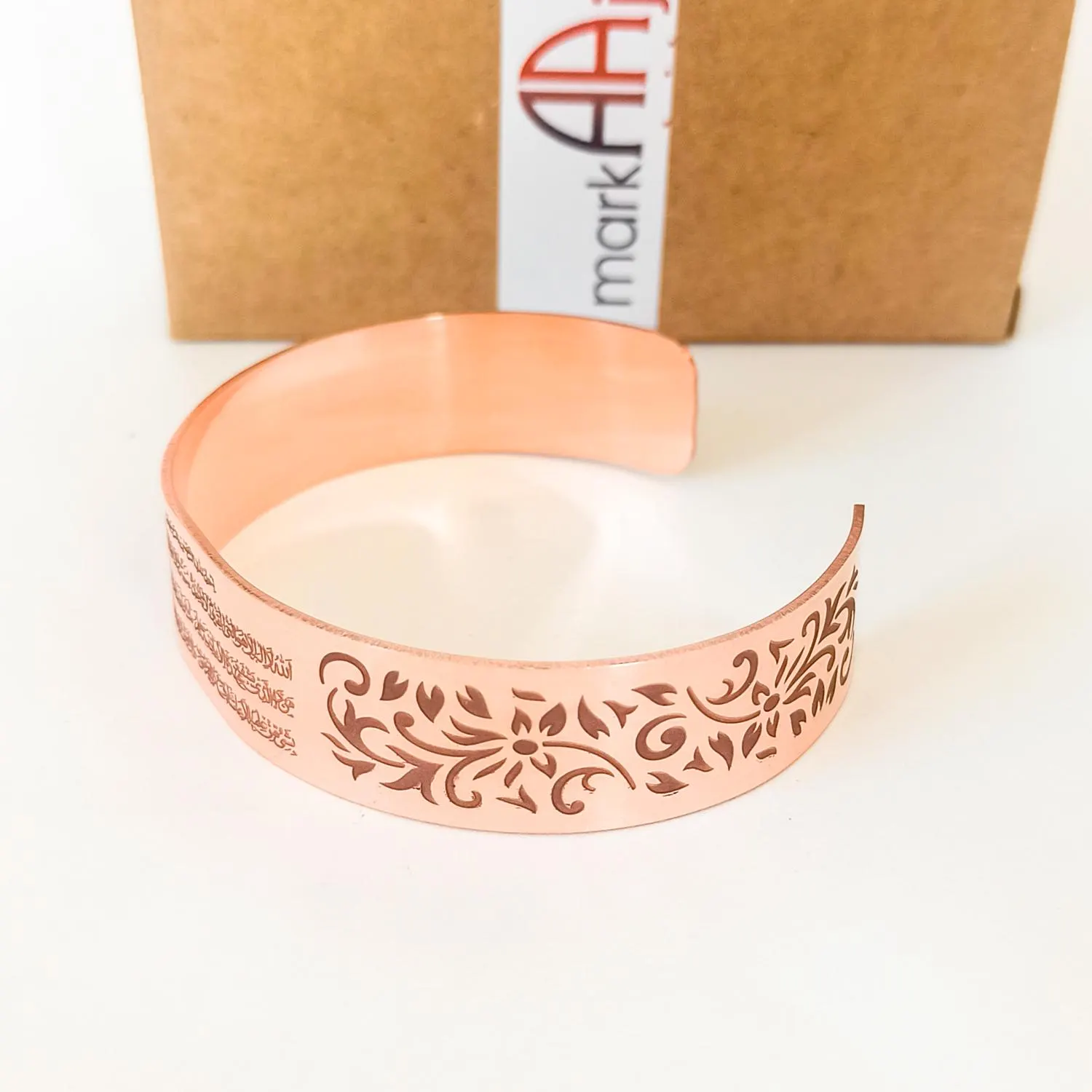 Side view of flexible Ayatul Kursi cuff in high quality copper. bracelet with an intricate floral design engraved on the surface. The bracelet is open and ready to be worn.