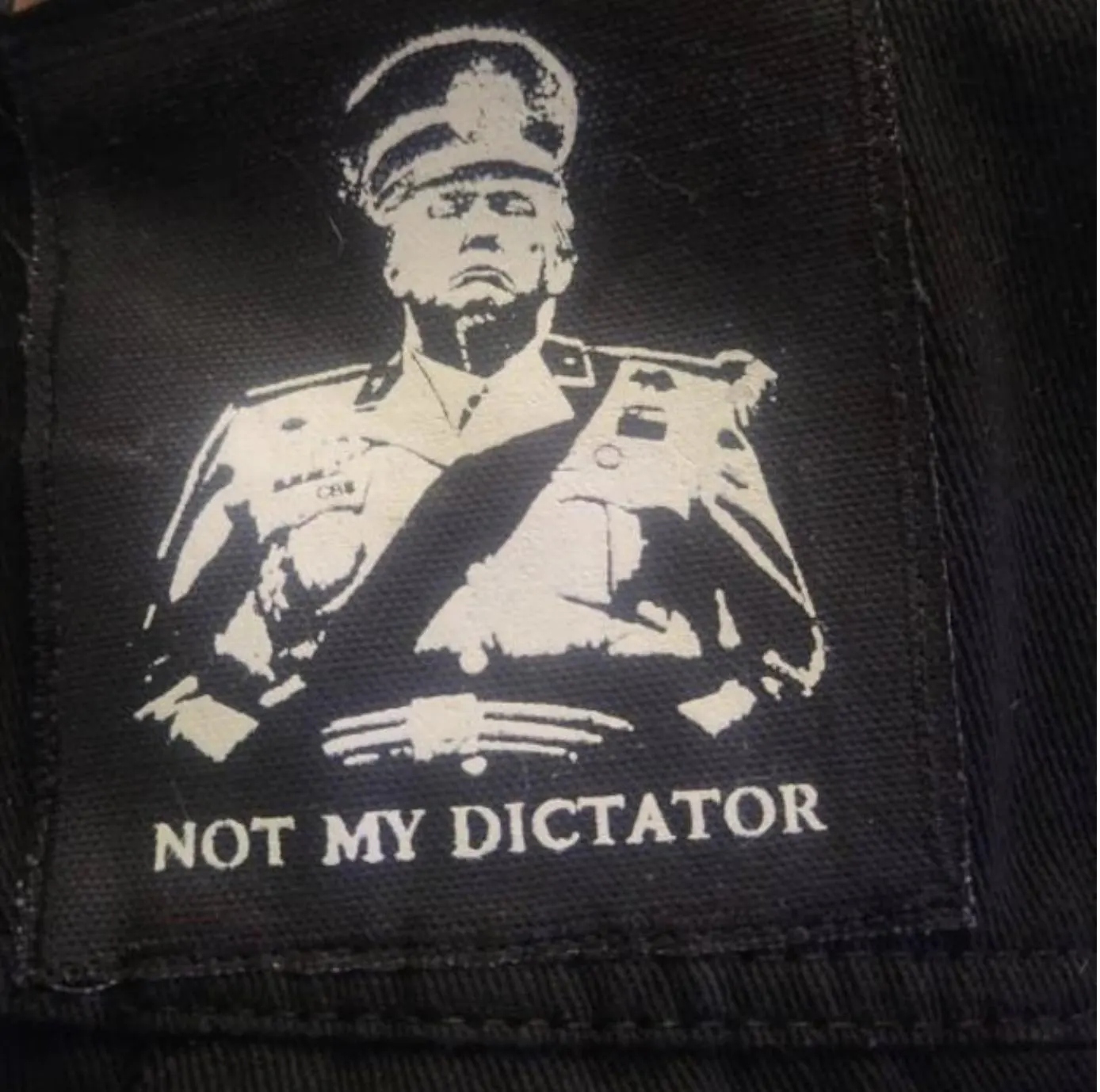 Close-up of anti-authoritarian punk patch attached to black denim jacket