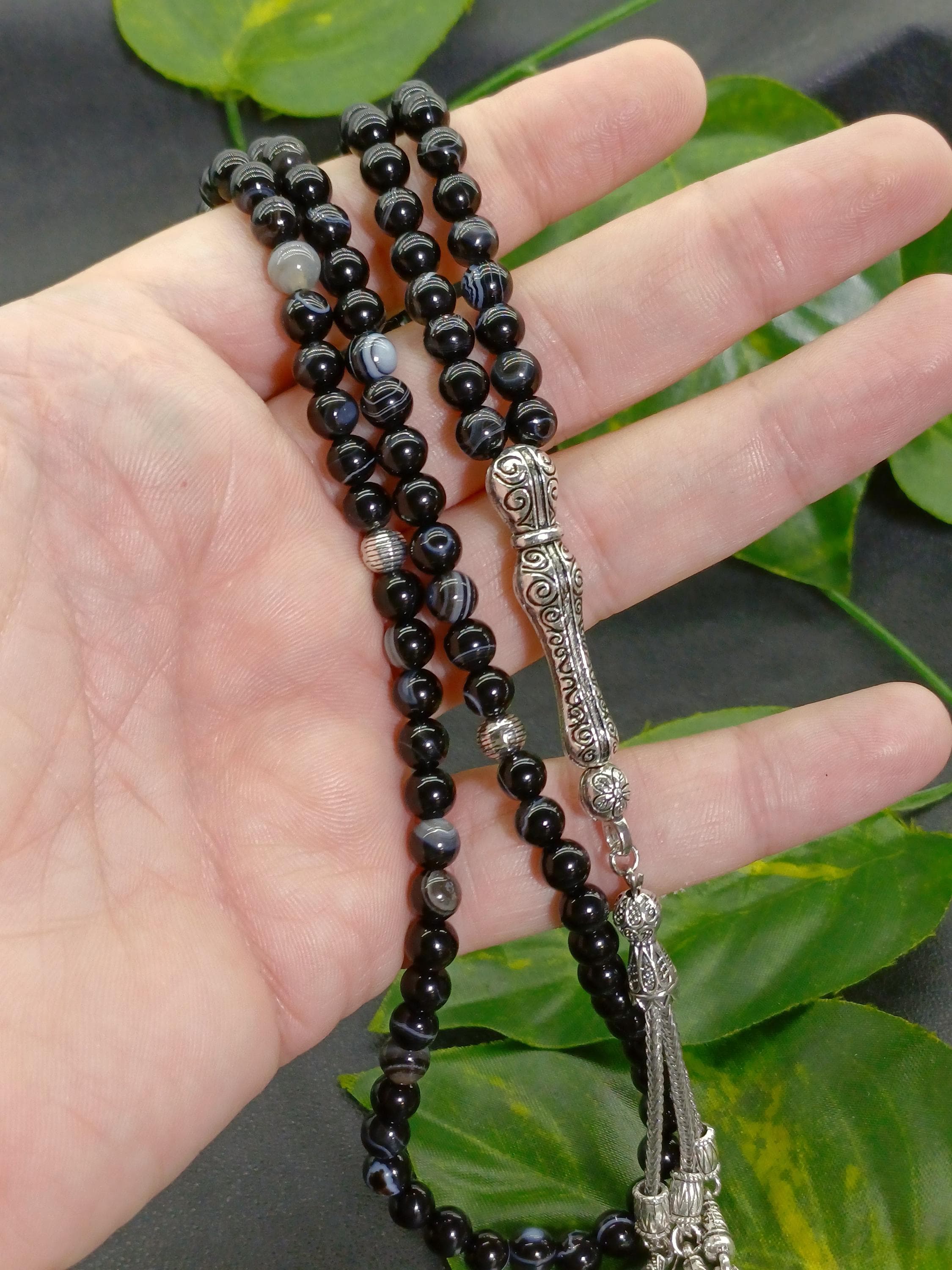 Man holding a small bead 99 black agate tasbih, compact and lightweight prayer beads for daily dhikr