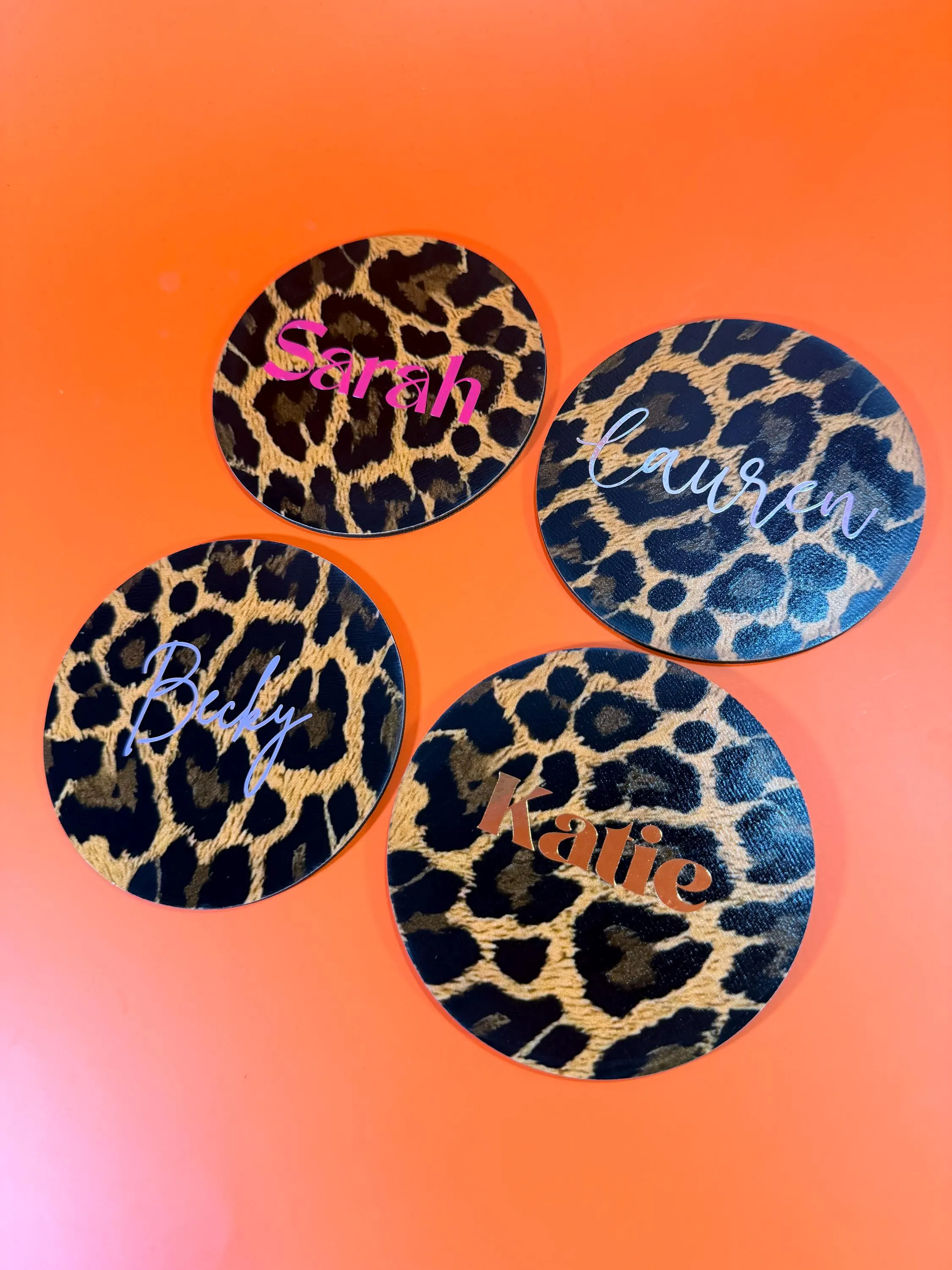 Personalised Coasters - Leopard Animal Print: Place Name Gifts
May include: Four circular coasters featuring a leopard print pattern. Each coaster displays a different name in a script font: Sarah, Lauren, Becky, and Katie. The coasters are set against an orange backdrop.
