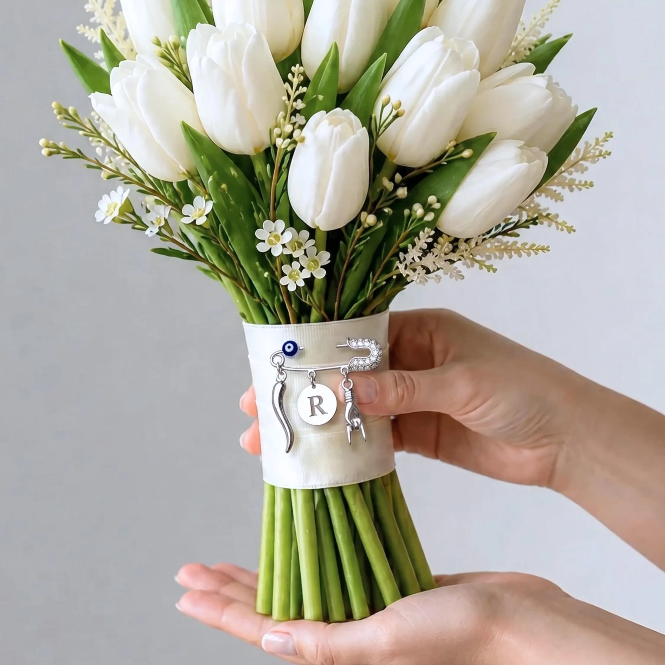 Silver color wedding charm personalized safety pin with Mano Cornuta, blue evil eye,  & Cornicello Italian horn charm attached to a bridal bouquet satin ribbon band.