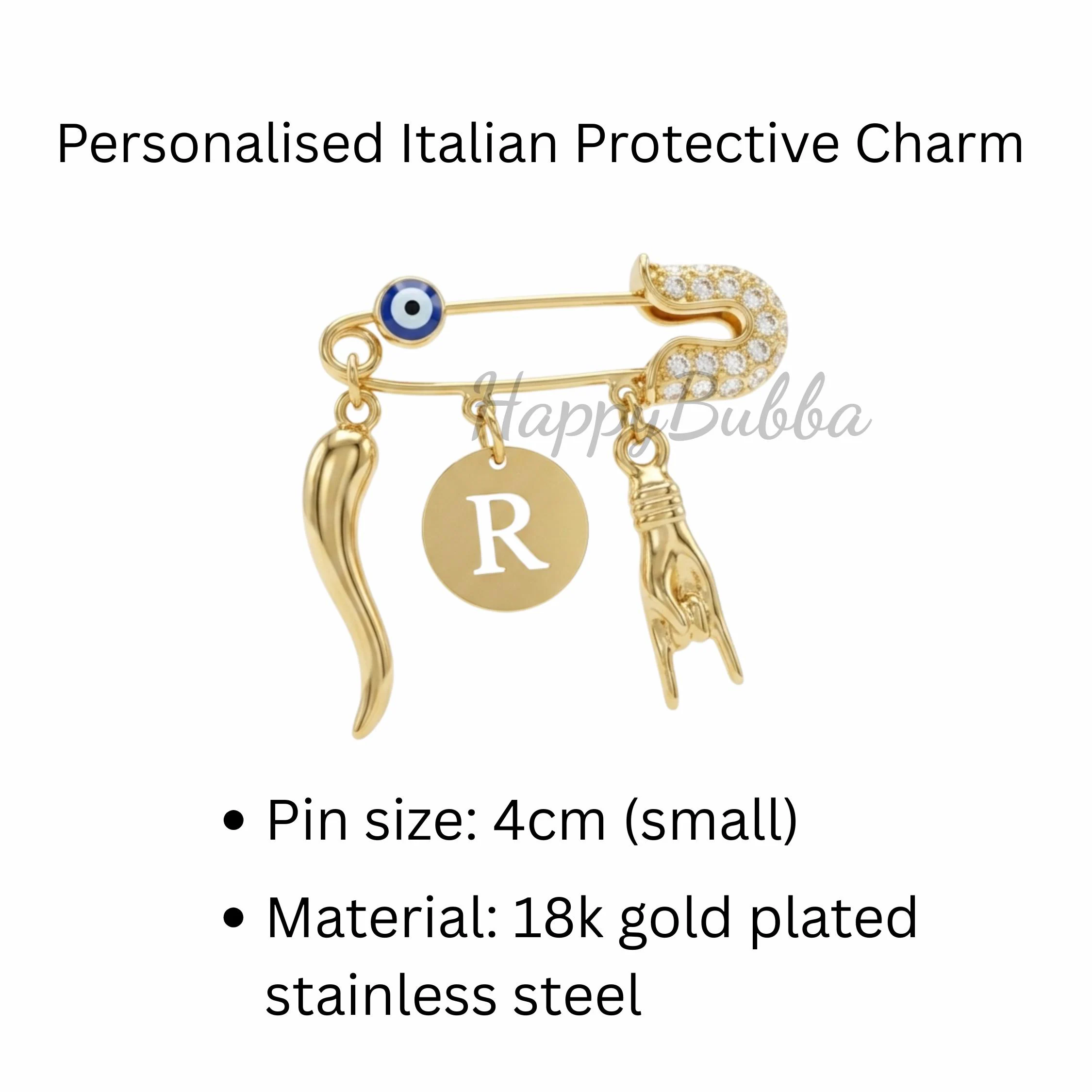 A gold-plated safety pin measuring 4cm, featuring a small blue and white evil eye bead, Italian horn charm, a round disc with the letter R, and a hand gesture mano cornuta charm. The pin head is encrusted with small clear stones.