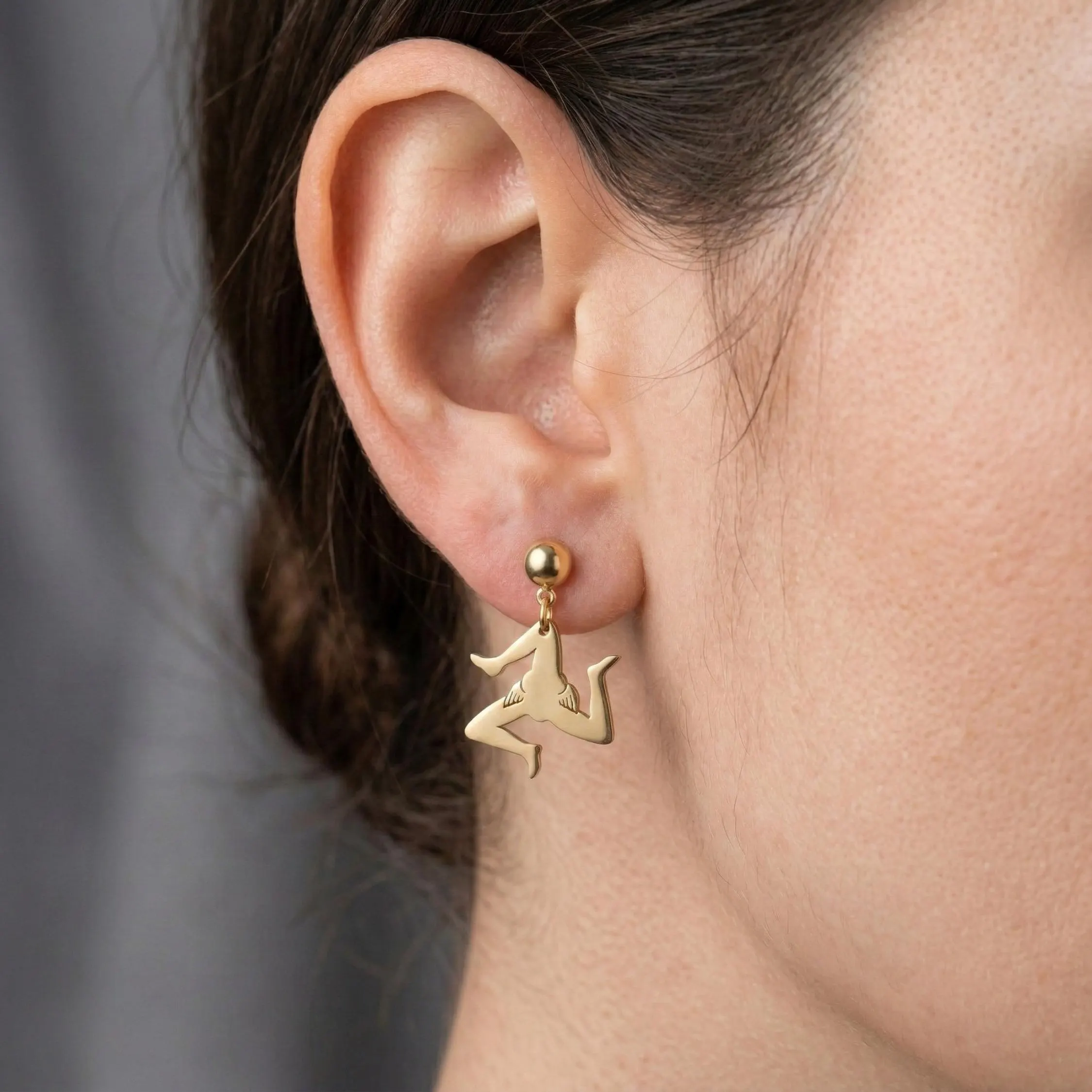 Sicilian Trinacria stud earring in gold plated stainless steel worn by a model.