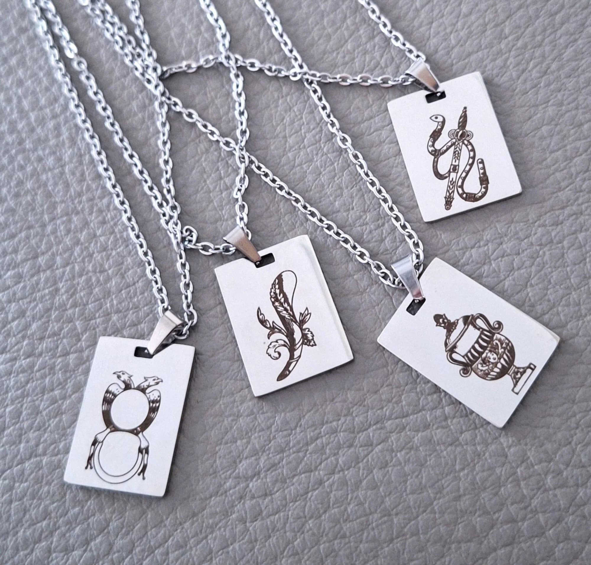Four silver necklaces with rectangular pendants featuring Scopa Briscola Italian playing cards game designs - Bastoni, Spada, Coppe, Denari.