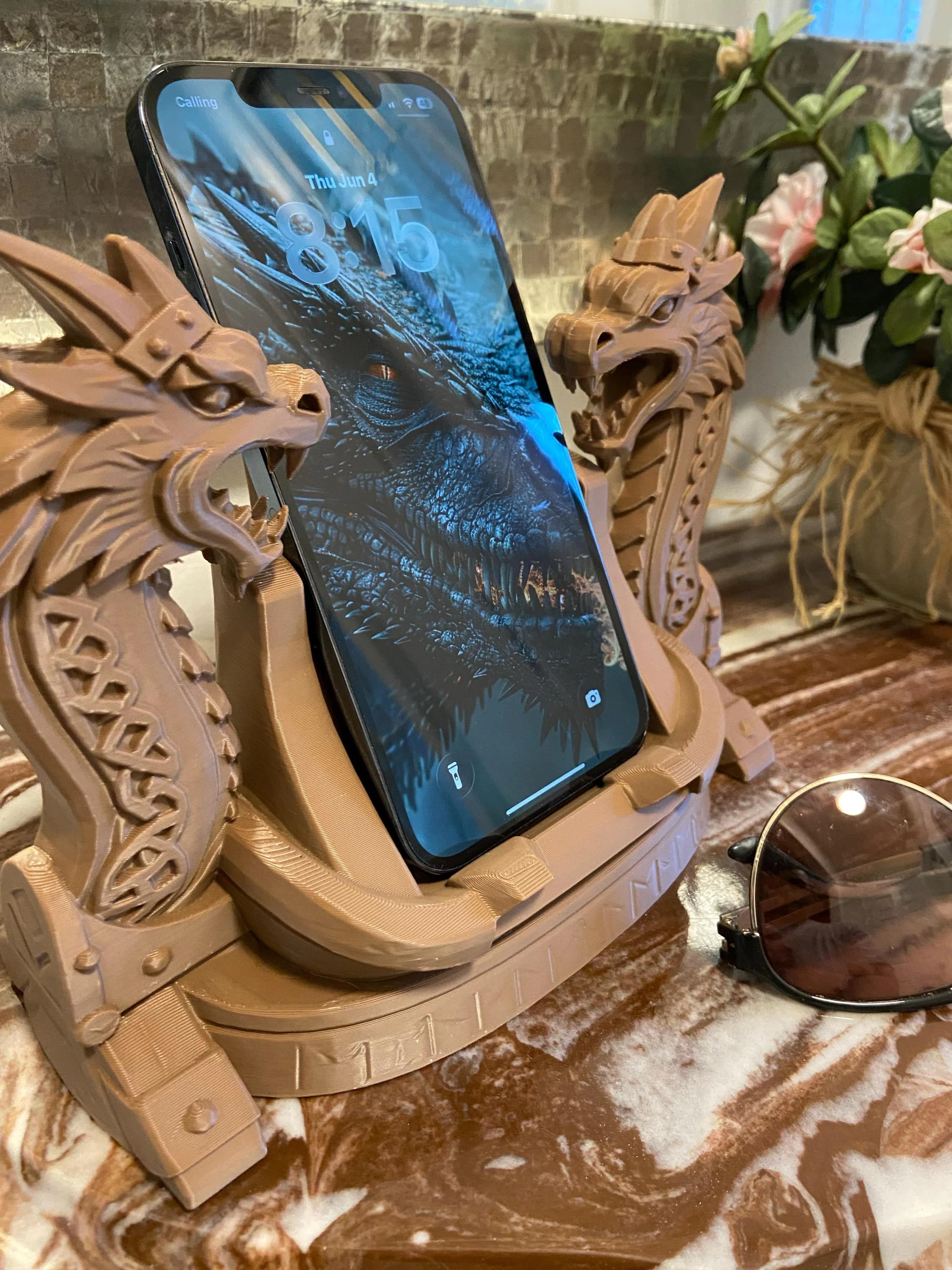 Light tan sandstone-colored 3D-printed dragon head phone stand, holding a smartphone.