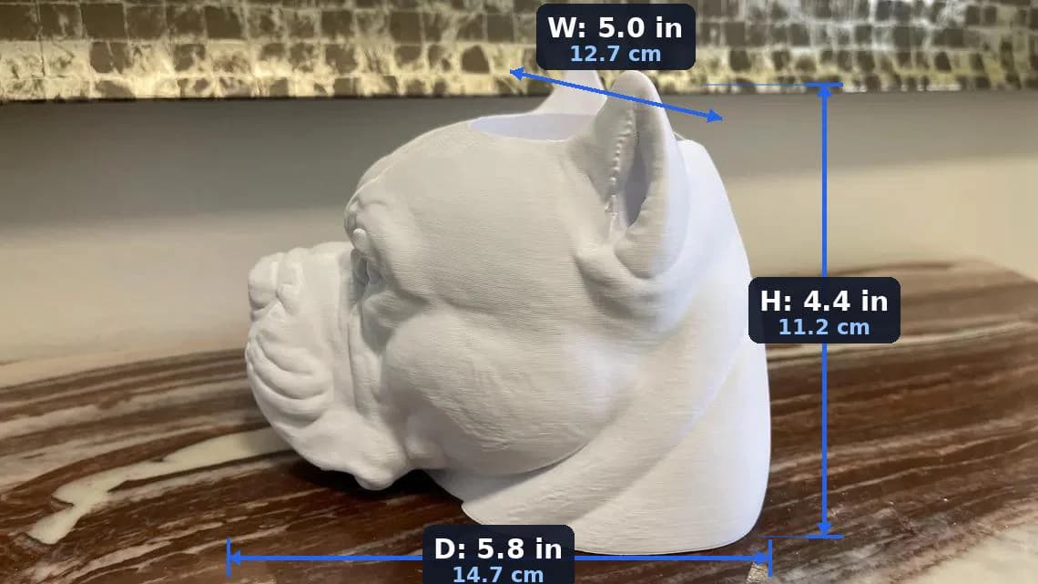 A white, 3D-printed sculpture of a dog's head, featuring detailed dimenstions and sizes as follows:
Width: 5.0 inches
Height: 4.4 inches
Depth: 5.8 inches