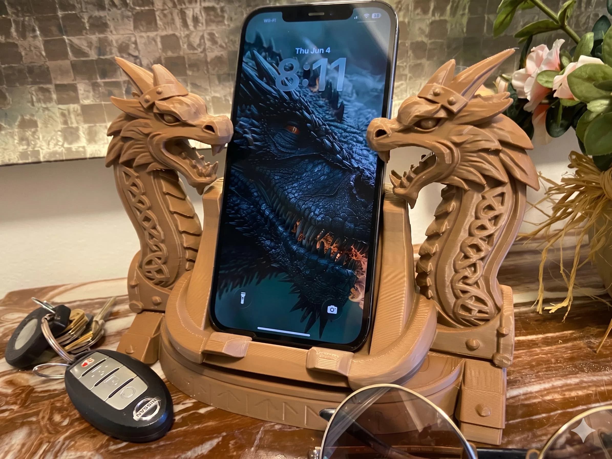 A rustic, dark wood-brown 3D-printed dragon phone stand, holding a phone on an antique desk.