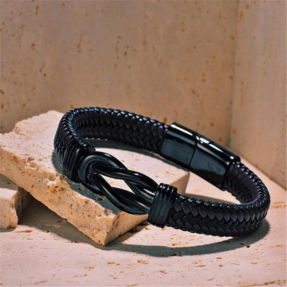 a black leather bracelet sitting on top of a rock