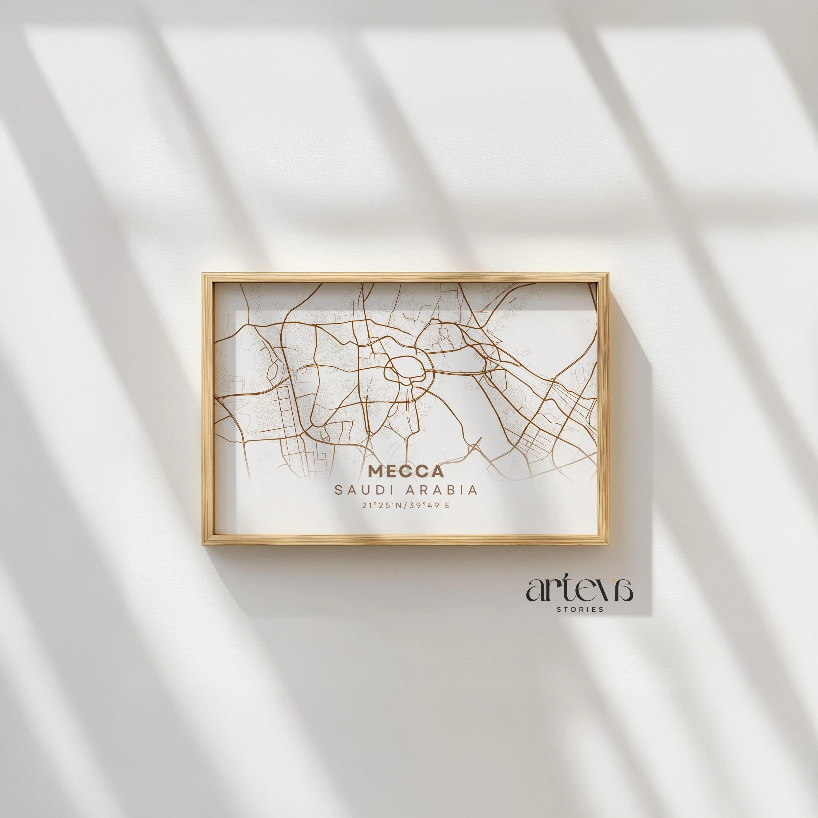 Frame on wall with sunlight – Minimalist Mecca city map poster in a natural wooden frame, displayed on a clean white wall with soft sunlight casting geometric shadows, highlighting the brown line art details and elegant typography.