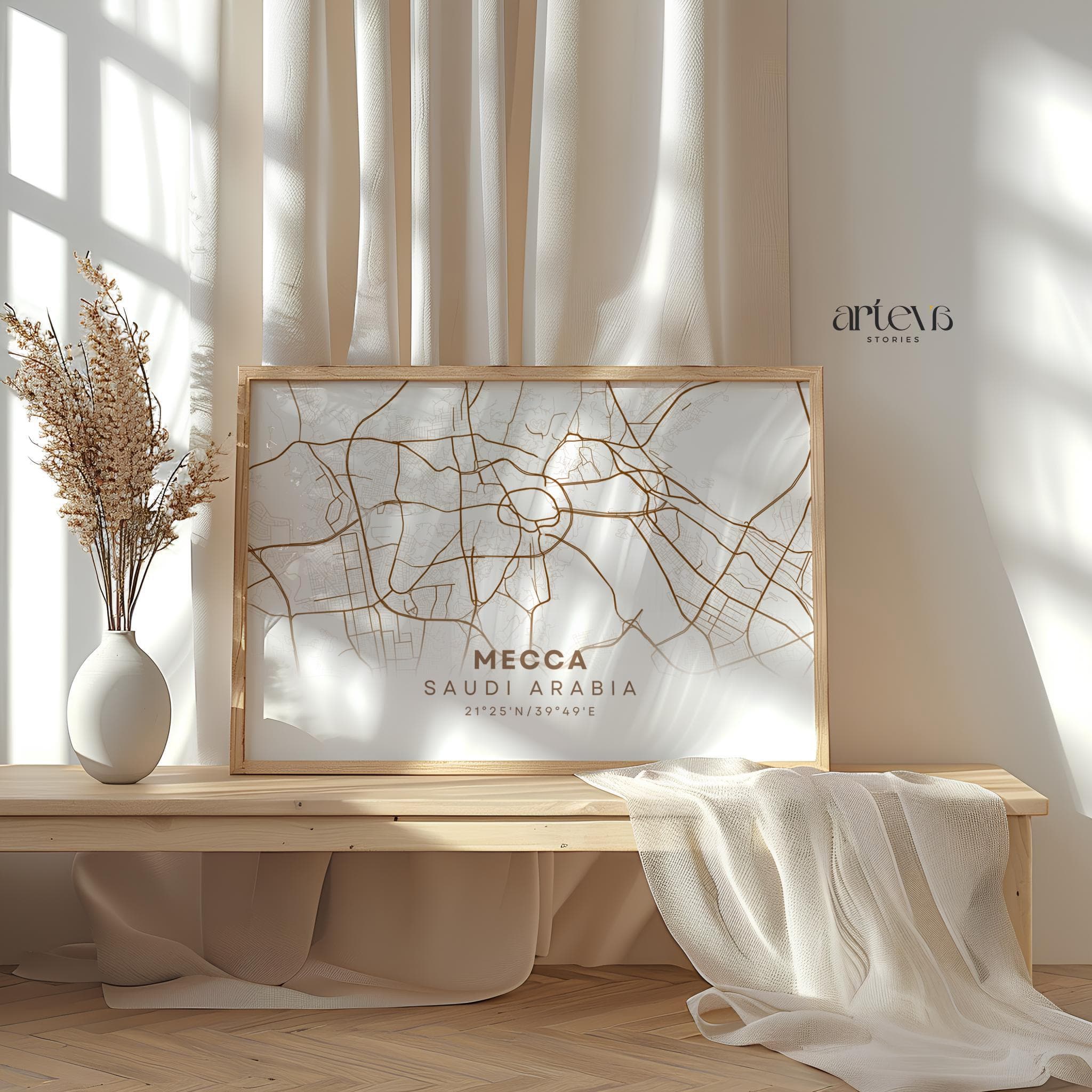 Poster leaning on bench – Mecca city map artwork in a wooden frame, leaning on a wooden bench with soft beige curtains, dried flowers in a ceramic vase, and a light draped cloth creating a serene and warm atmosphere.