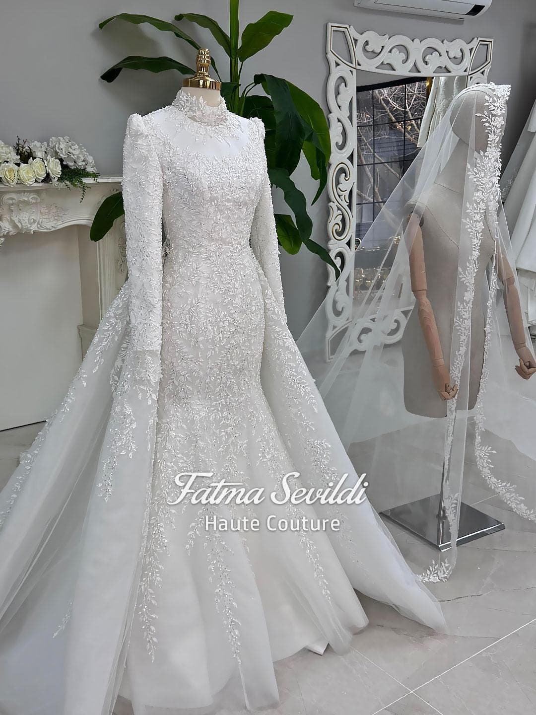 Veiled hijab wedding dress in a modest mermaid silhouette with detachable overskirt, long sleeves and high neck, handcrafted with beaded lace. Includes a matching premium lace veil for a luxury Muslim bridal set.
