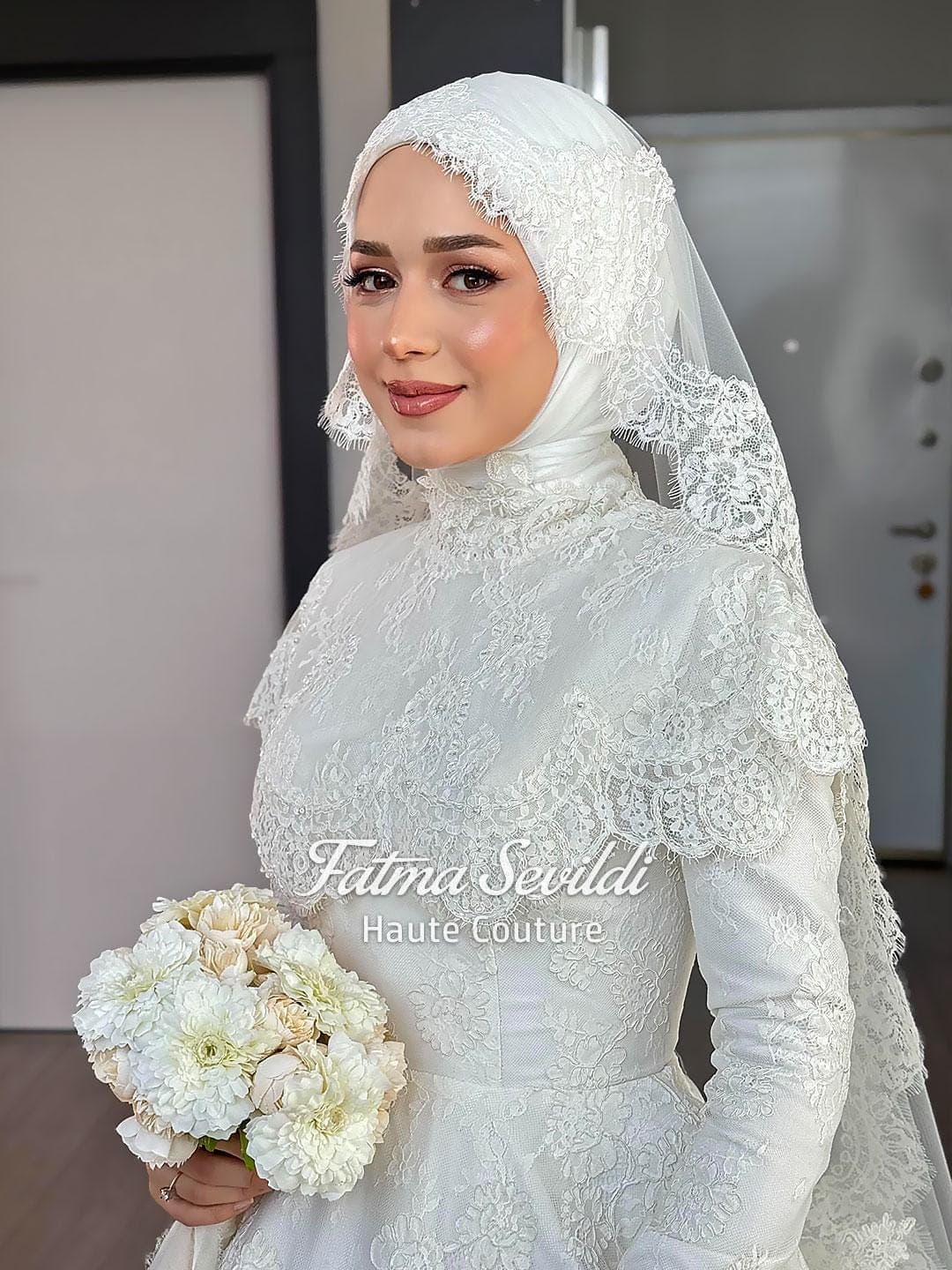 Veiled hijab wedding dress with high neck, long sleeves, and couture beaded lace in a structured ball gown silhouette. Includes pearl veil set for an elegant modest bridal look.