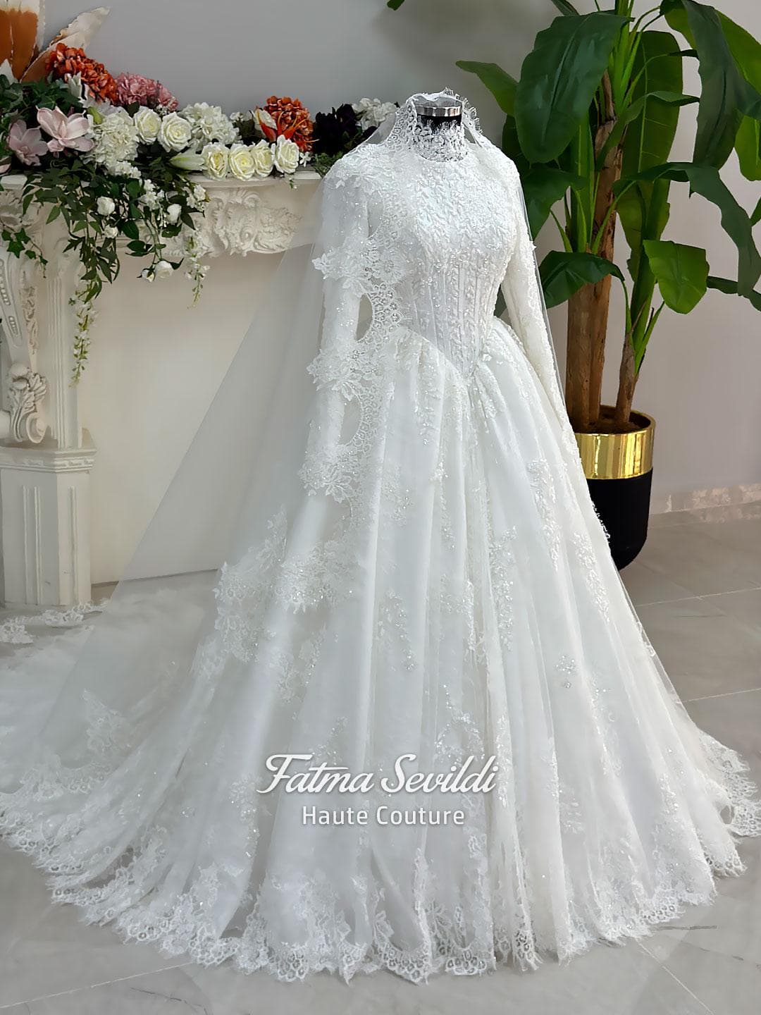 Luxury modest hijab wedding dress ball gown with long sleeves, high neck corset bodice, lace appliqué and included lace veil, photographed in a bridal atelier.