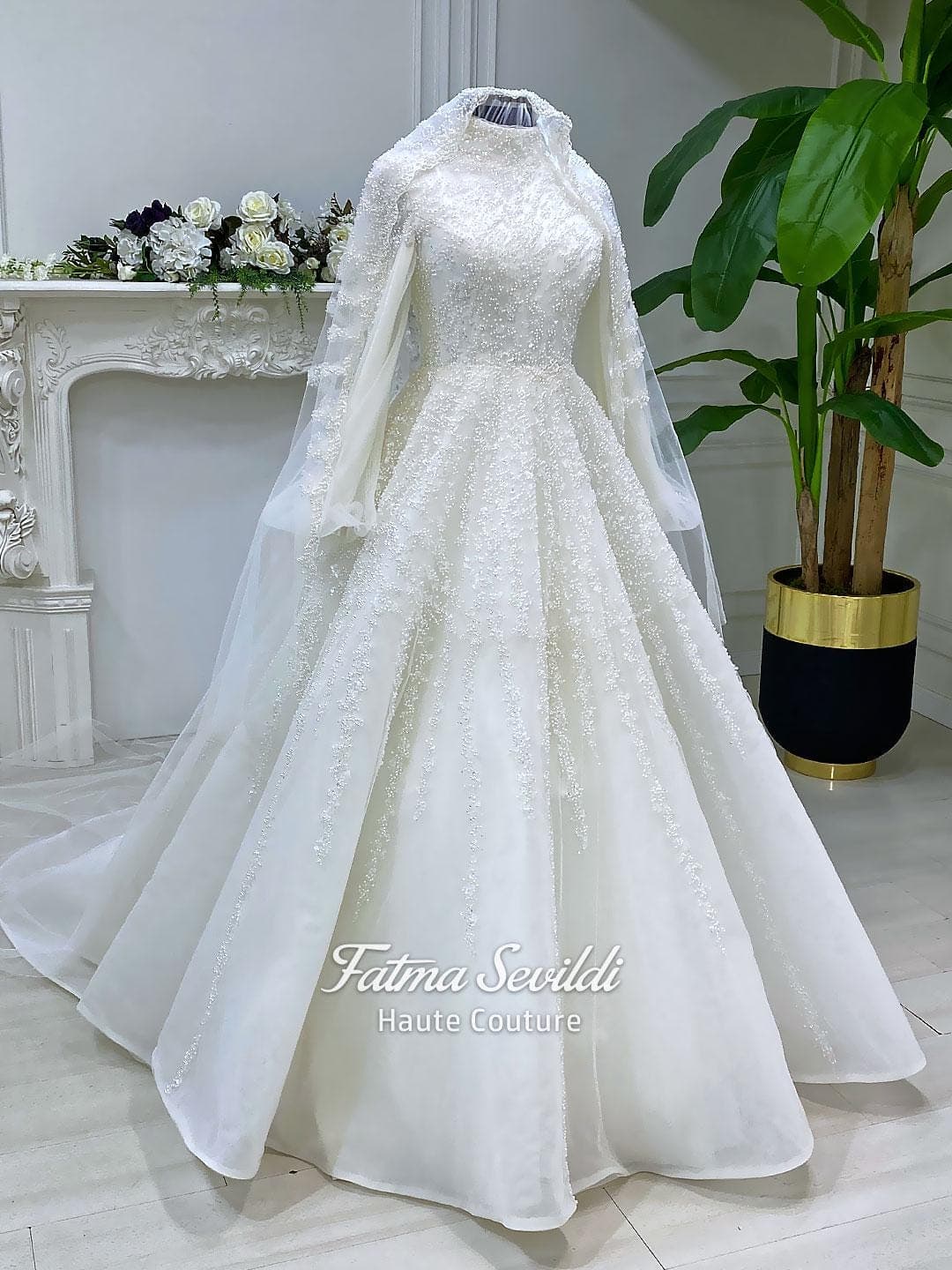 Luxury hijab wedding dress in an A-line tulle ball gown silhouette with long balloon sleeves, high neck, sparkling beadwork, and a lace-edged veil.