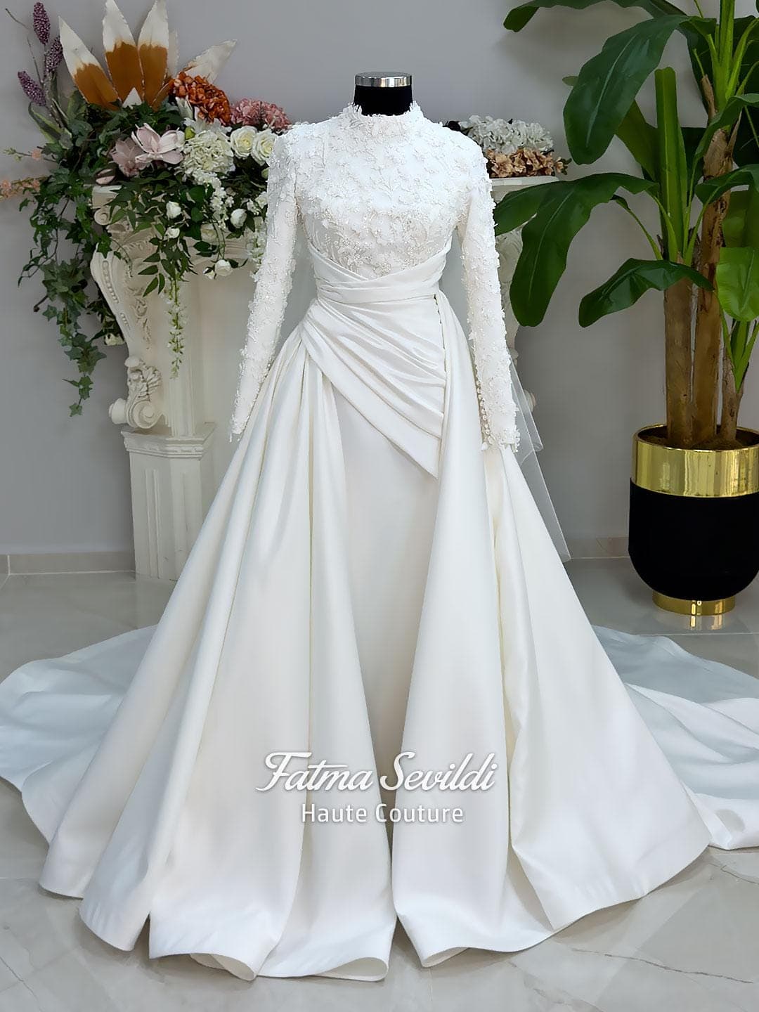 Luxury modest hijab wedding dress with long sleeves, 3D floral beaded lace bodice, draped satin A-line skirt and lace-edged veil included, shown on mannequin. Custom made Islamic bridal gown with elegant full coverage.
