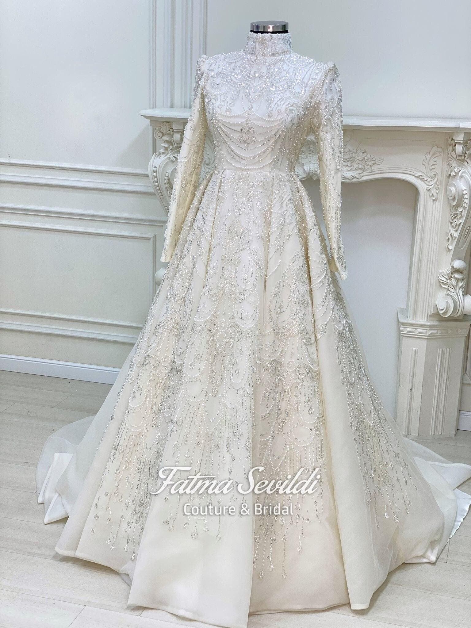 Luxury hijab wedding dress with high neck, long sleeves, and hand-beaded lace on an A-line modest bridal gown, custom made.