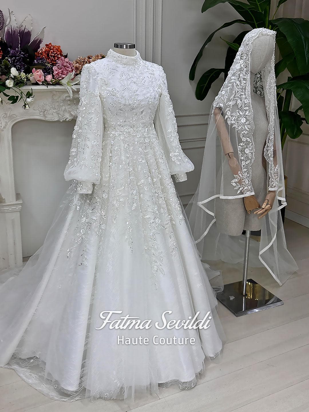 Luxury hijab wedding dress with high neck, long sleeves, beaded embroidery, full skirt, and matching premium lace veil. Elegant modest bridal gown designed for Muslim brides seeking a couture wedding look.