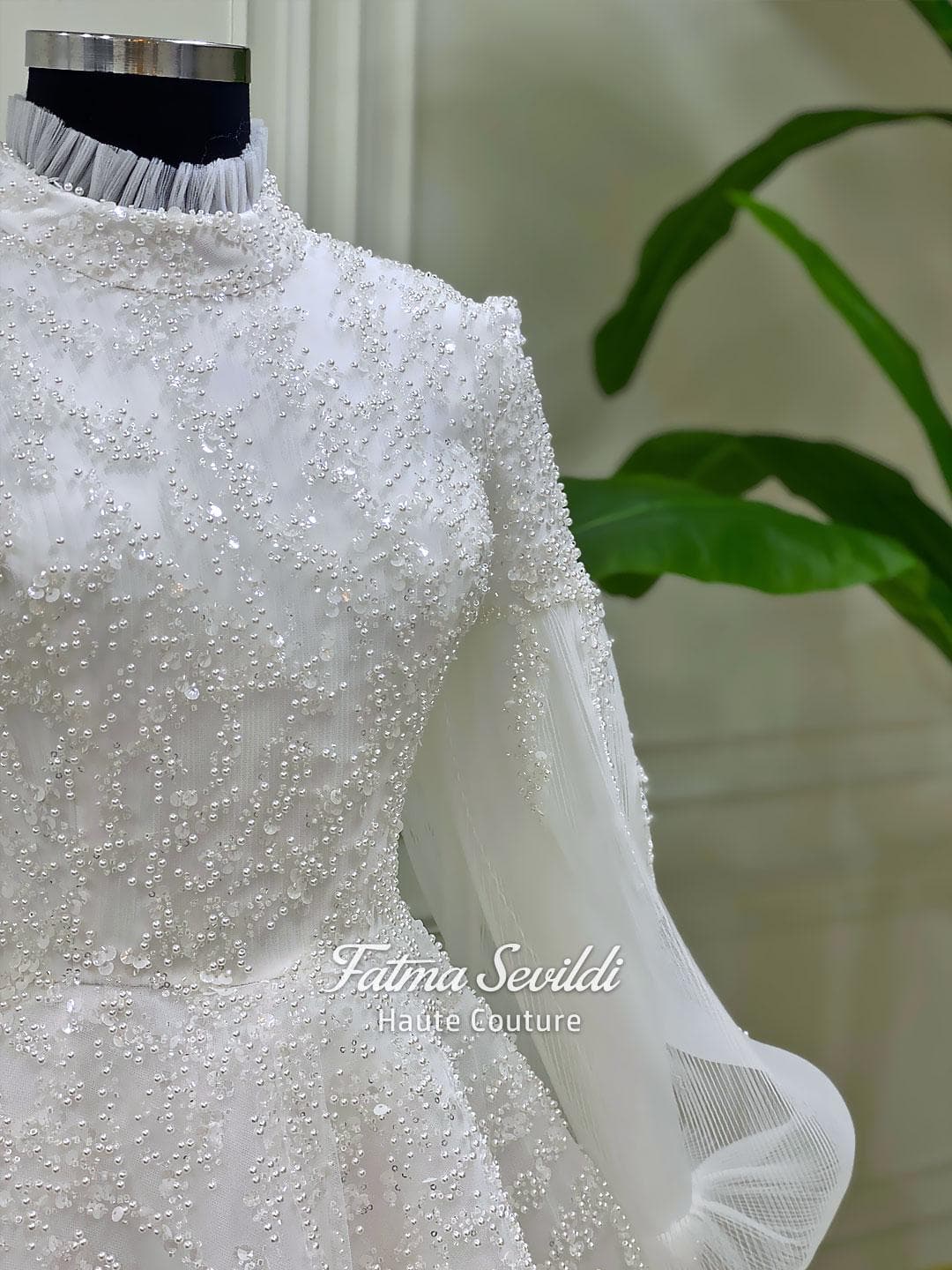 Luxury hijab wedding dress in an A-line tulle ball gown silhouette with long balloon sleeves, high neck, sparkling beadwork, and a lace-edged veil.