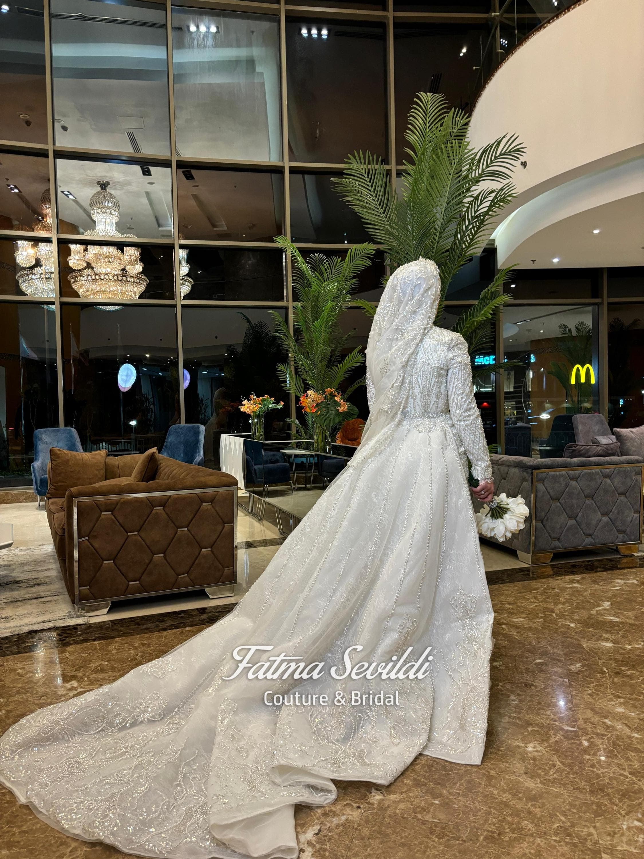 Luxury veiled hijab wedding dress with high neck, long sleeves, and hand-finished beaded lace in an A-line ballgown silhouette. Premium lace-edge veil included for a complete modest bridal look.