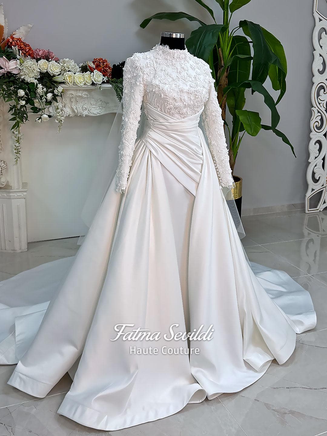 Luxury modest hijab wedding dress with long sleeves, 3D floral beaded lace bodice, draped satin A-line skirt and lace-edged veil included, shown on mannequin. Custom made Islamic bridal gown with elegant full coverage.