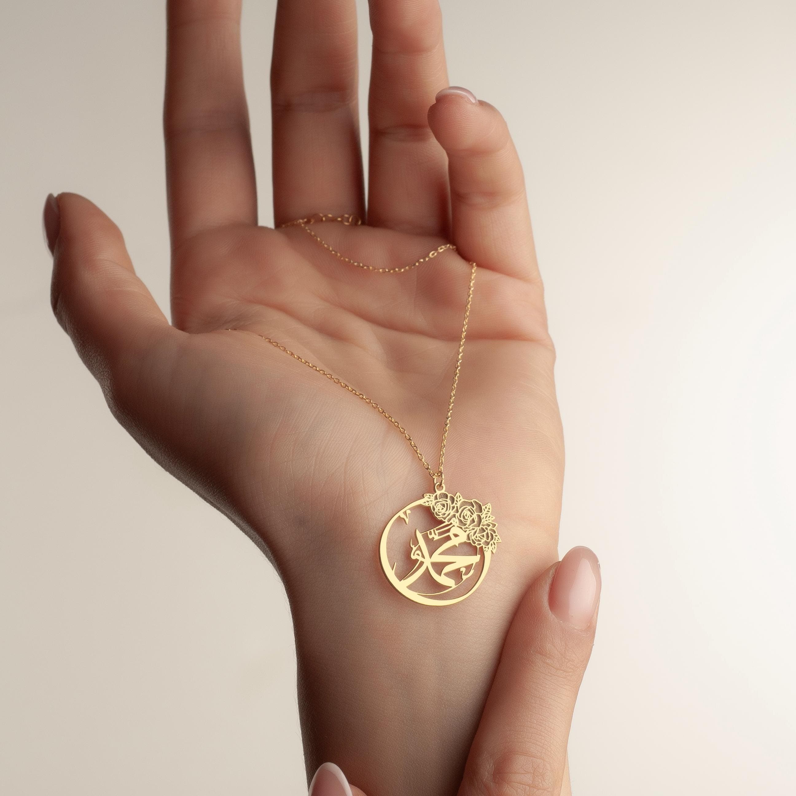 ✨ Carry Your Faith, Elegantly. ✨

This handcrafted Muhammad (PBUH) name necklace is more than just jewelry—it's a symbol of faith, beauty, and devotion you can wear every day. Designed with a delicate rose motif and inscribed with the name of the Prophet, this pendant blends spiritual meaning with timeless elegance.A gold necklace with a circular pendant featuring a floral design and Arabic calligraphy.