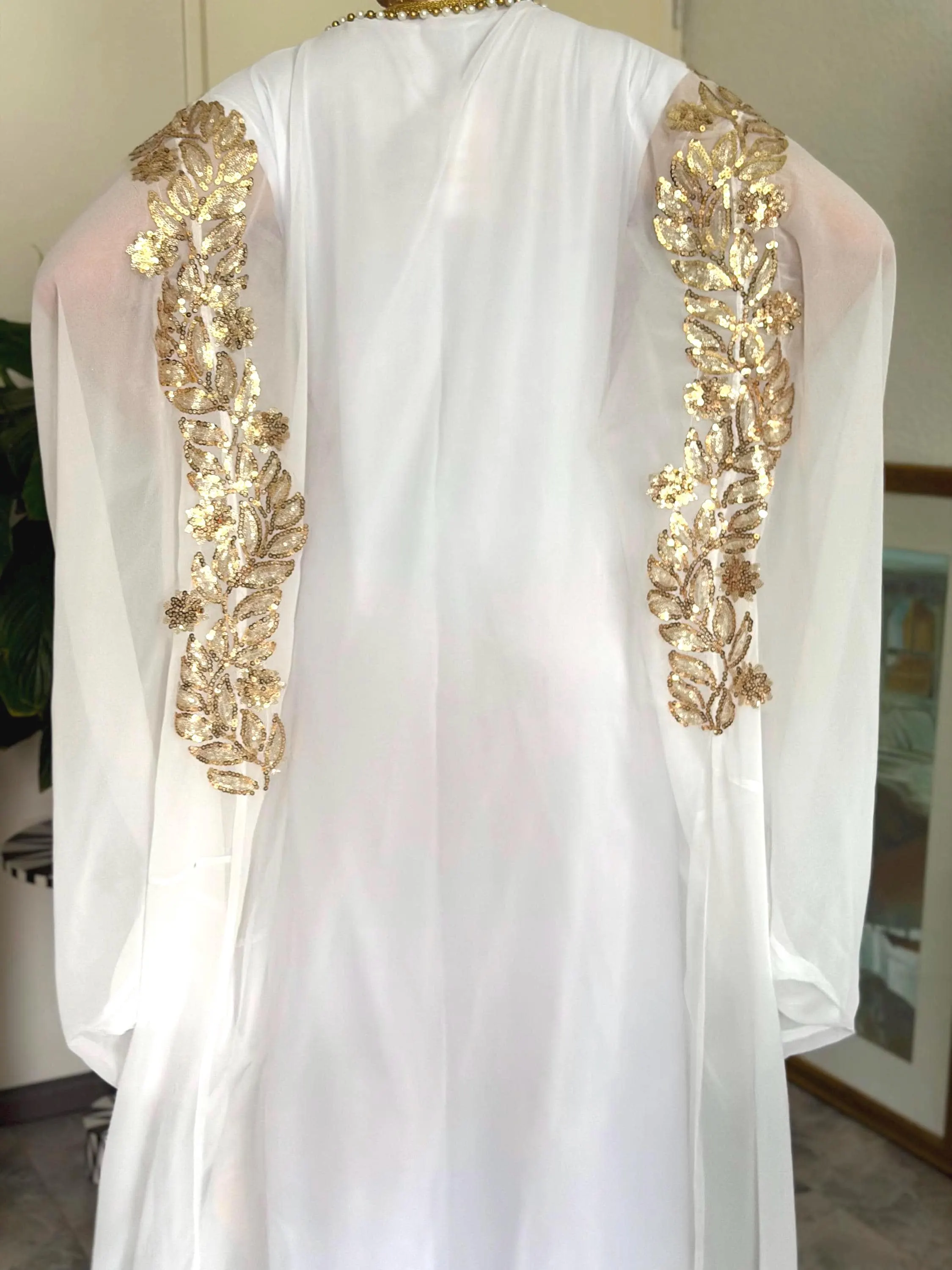 Handmade white Iraqi Hashmi chiffon gown, luxury Arabic abaya, gold sequined floral embroidery, flowing butterfly sleeves, pearl beaded details, decorative gold trims, modest maxi dress, traditional Middle Eastern heritage fashion, elegant wedding, Eid and occasion wear, matching underdress included.