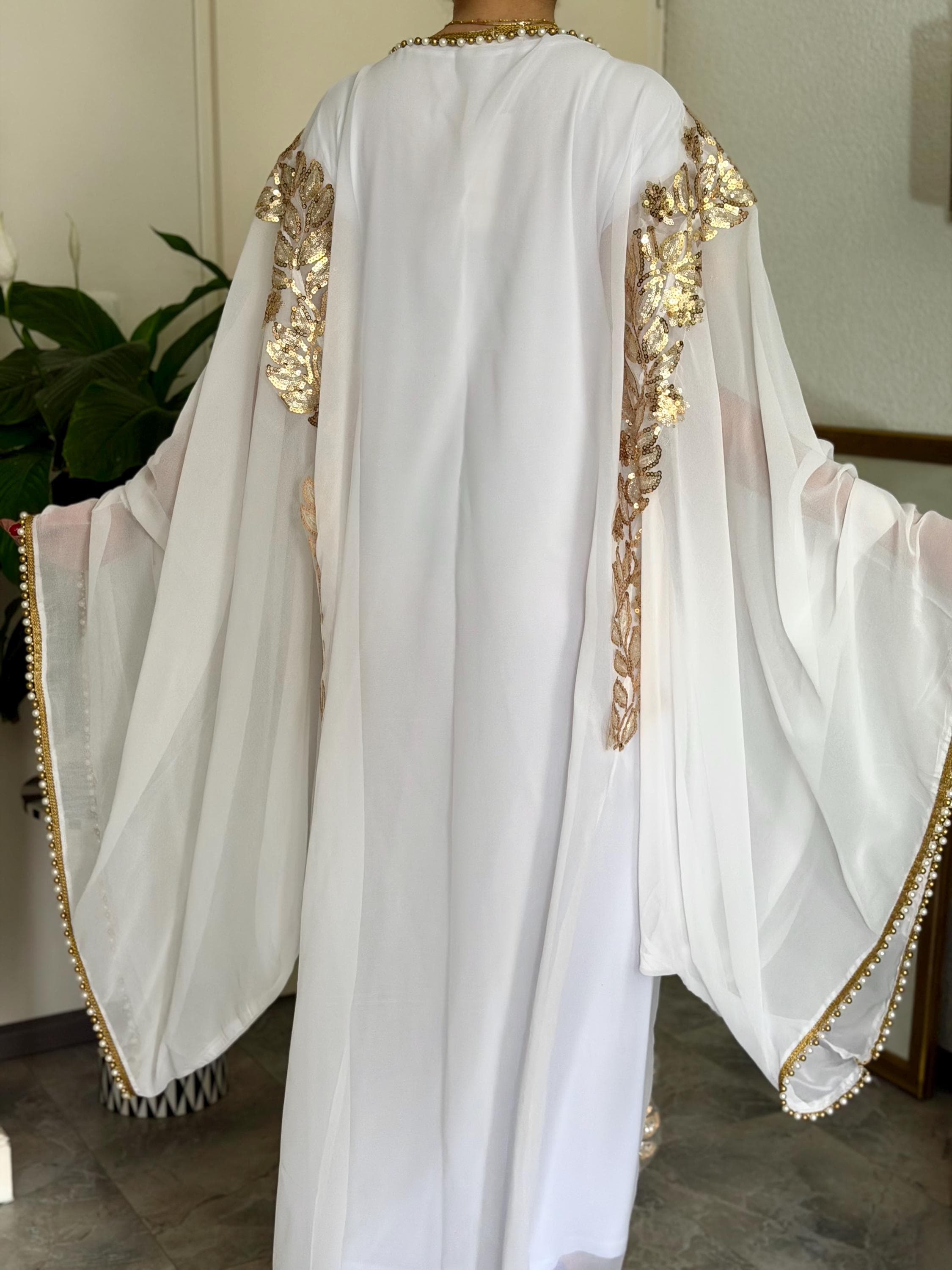 Traditional Iraqi Hashmi dress, white chiffon luxury abaya, gold floral embroidery, shimmering sequins, pearl bead embellishments, long butterfly sleeves, handcrafted modest maxi gown, Arabic heritage fashion, bridal inspired occasion wear, artisan craftsmanship, matching underdress included.