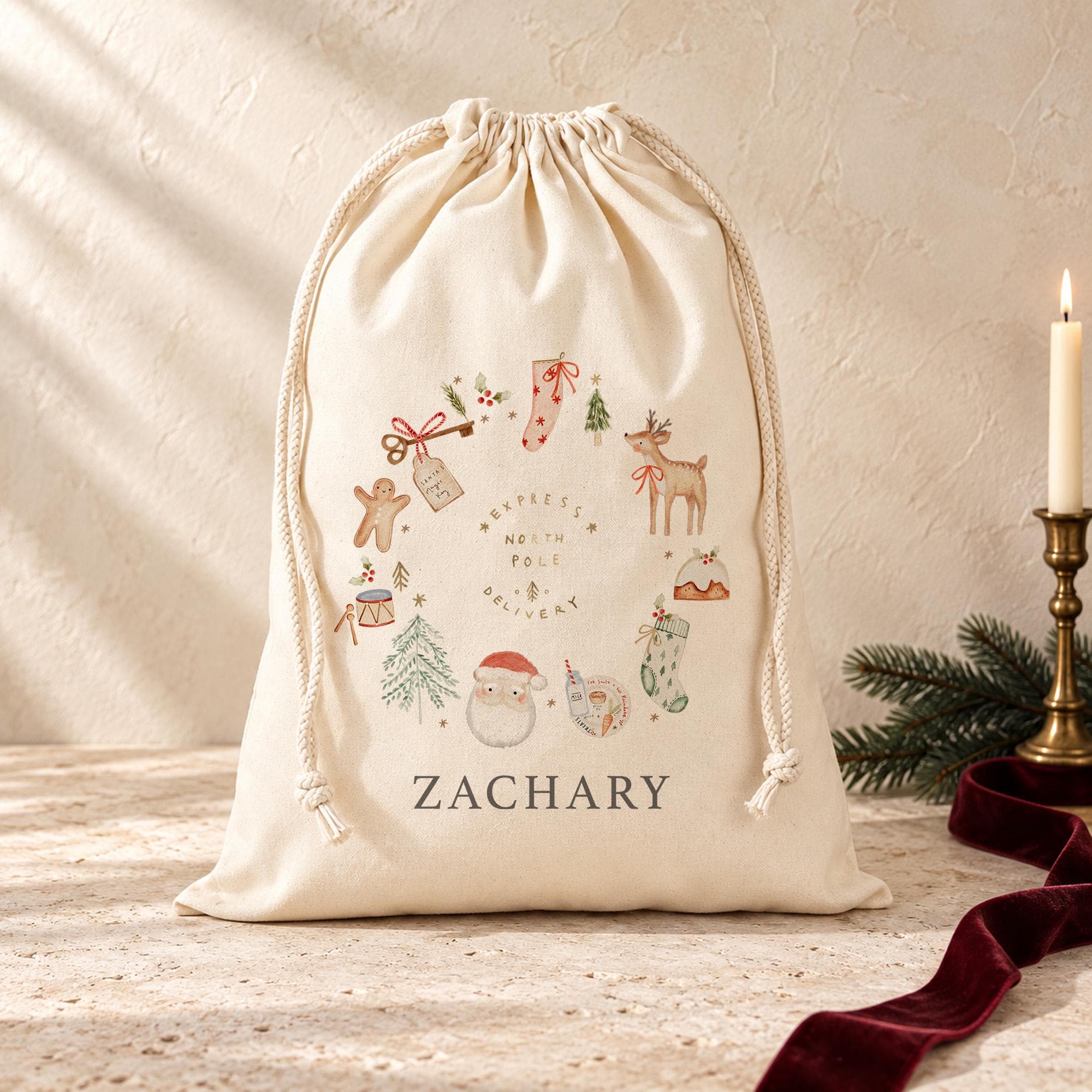 Cream drawstring Santa sack with a traditional Christmas wreath design and the name ZACHARY in capital letters, styled with a candle, pine sprig and red velvet ribbon