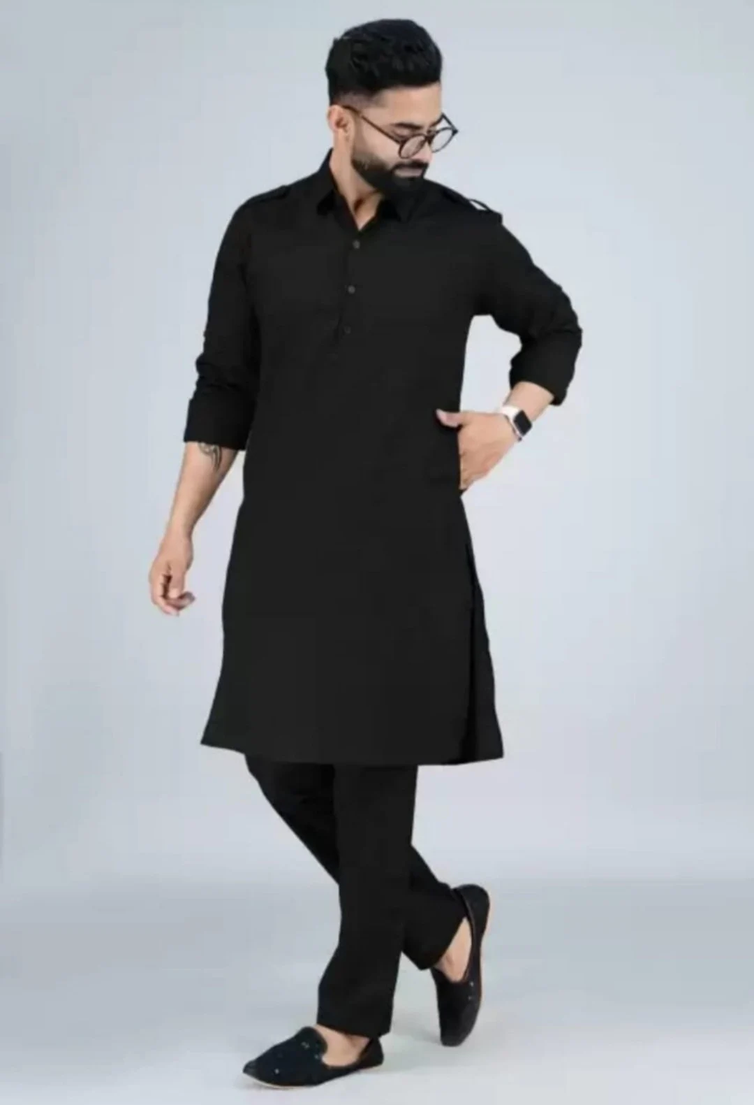 May include: A black long-sleeved kurta with a button-up collar and a matching pair of black pants. The man is wearing black shoes.