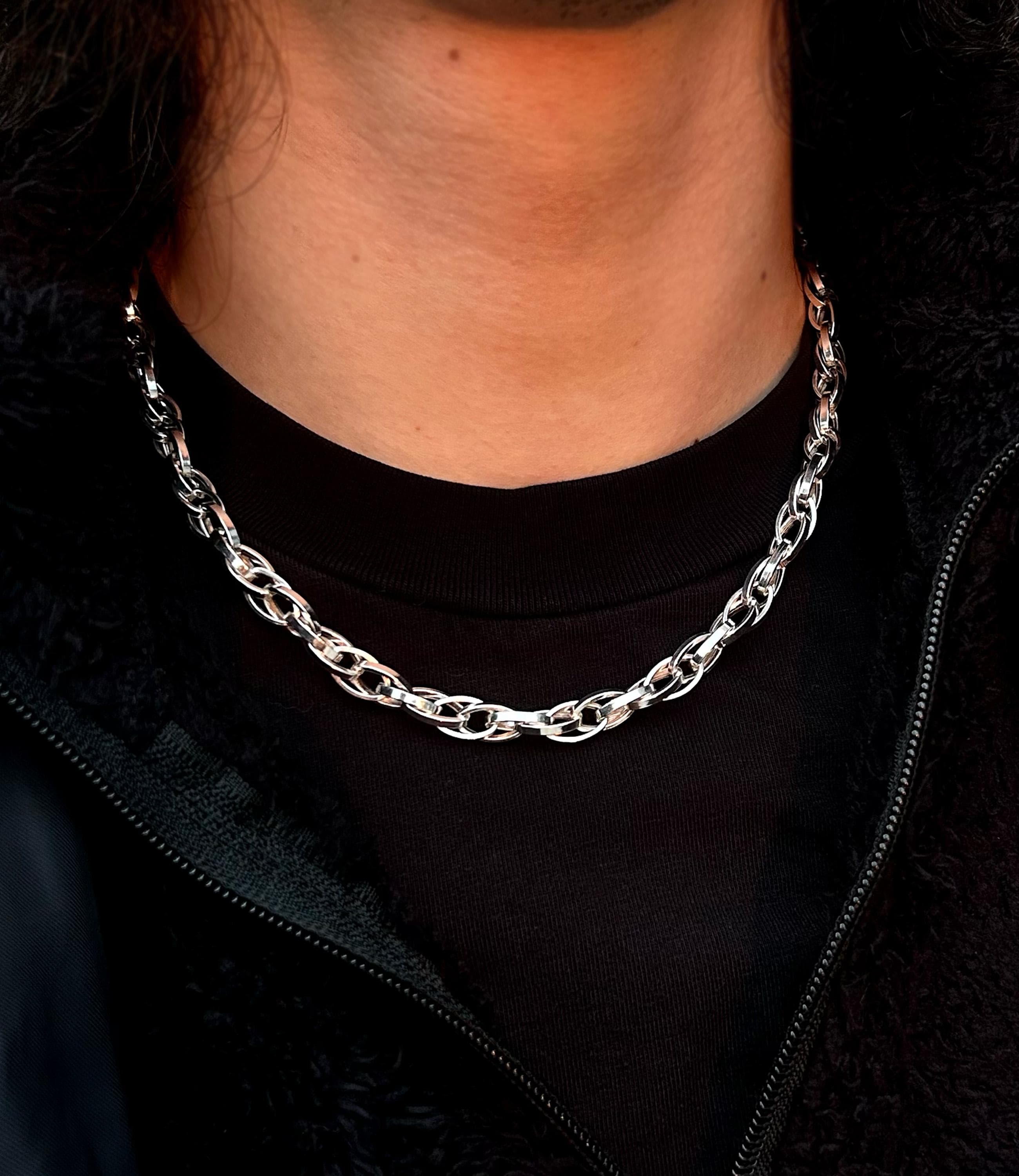 A unique 925 sterling silver paperclip necklace with complex, interlocking oval links, draped to show its intricate woven texture and high-polish finish.