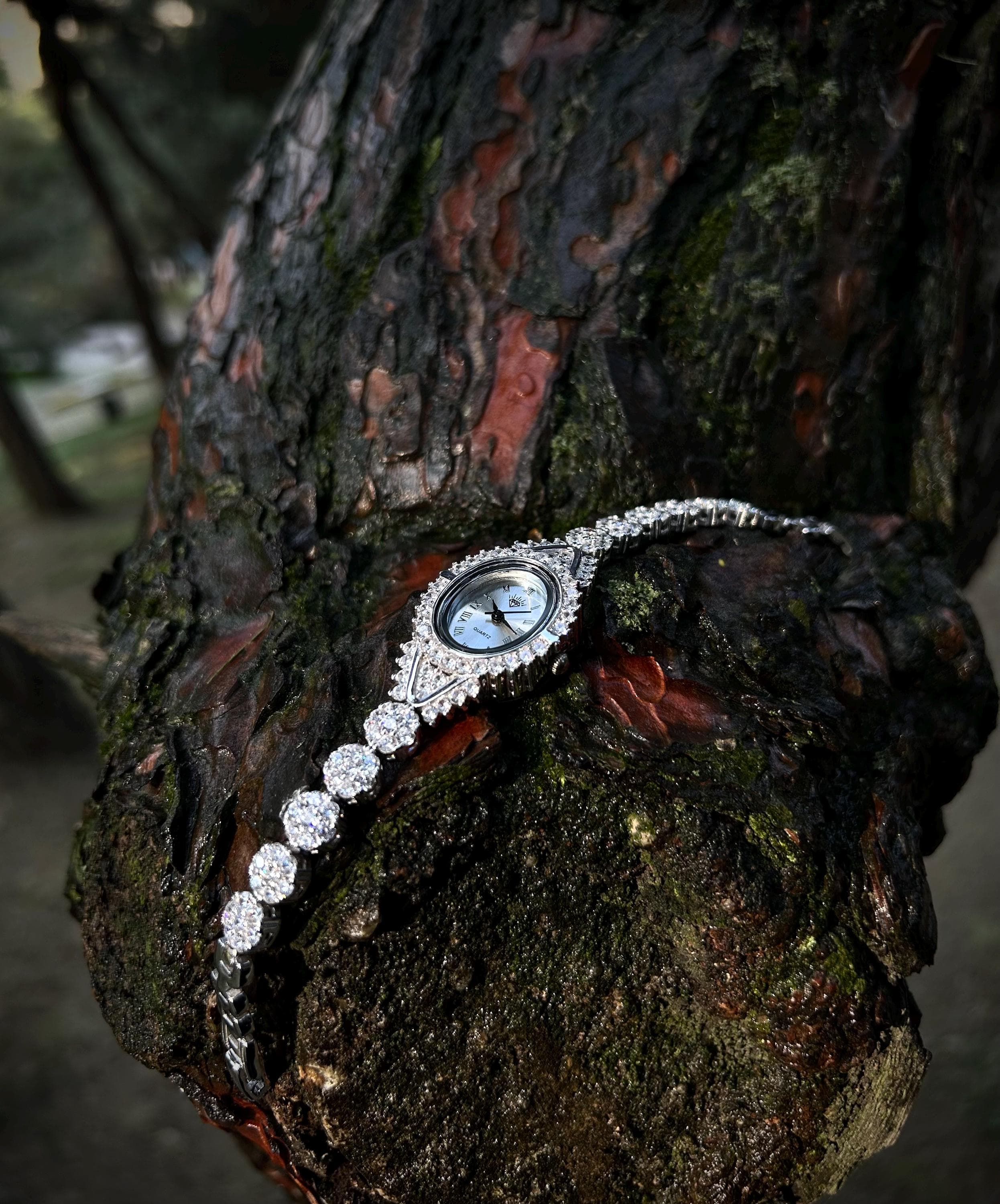 A rhodium plated luxury women's watch handcrafted from 925 sterling silver, featuring iced zircon stones. Shown with a Phoenix necklace gift option on a black textured background. Ideal for Mother's Day or luxury gift occasions.