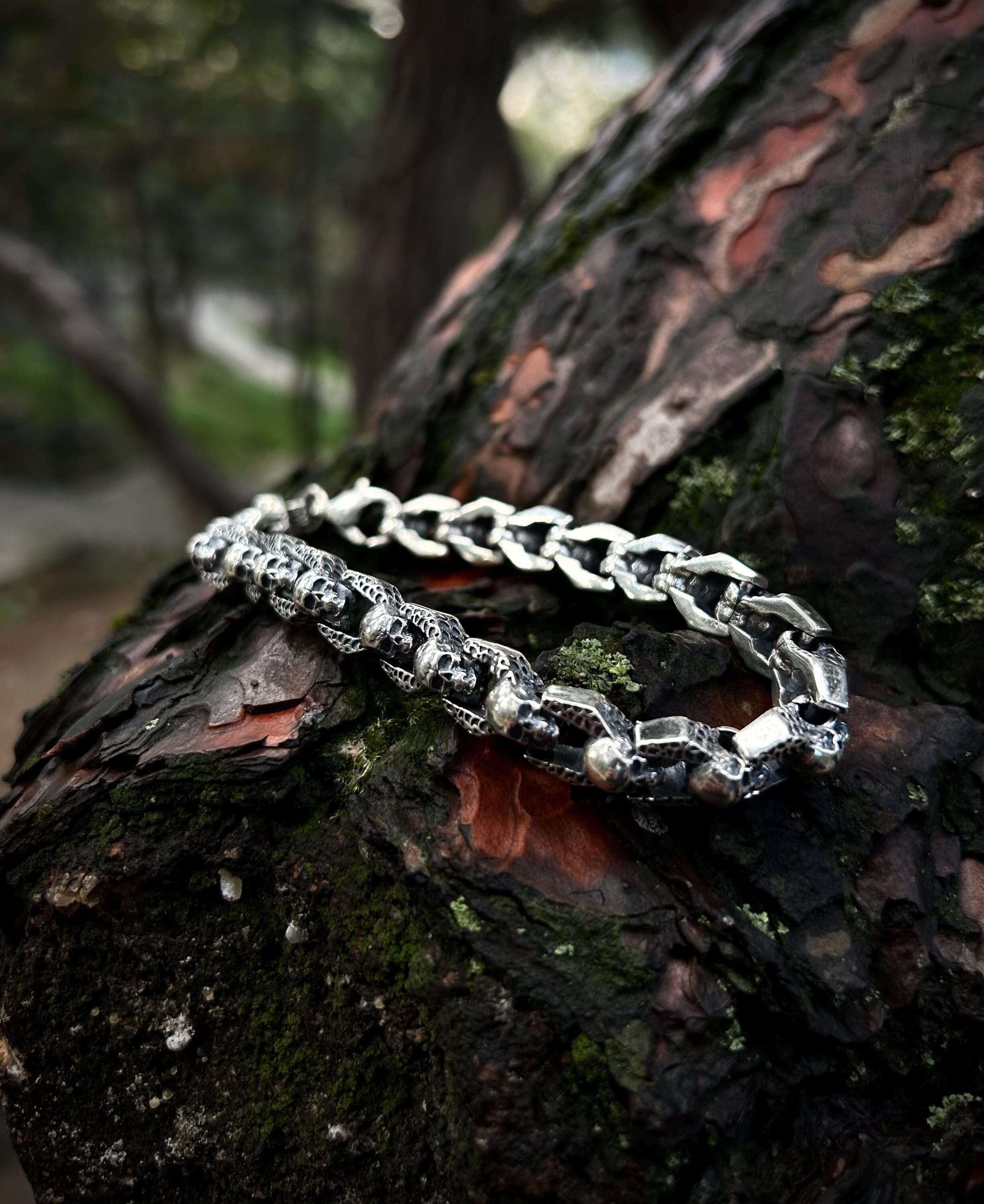 925 sterling silver skull chain bracelet with gothic detailing, featuring high-polish skull links, photographed on dark leather to highlight its edgy, handcrafted biker design.