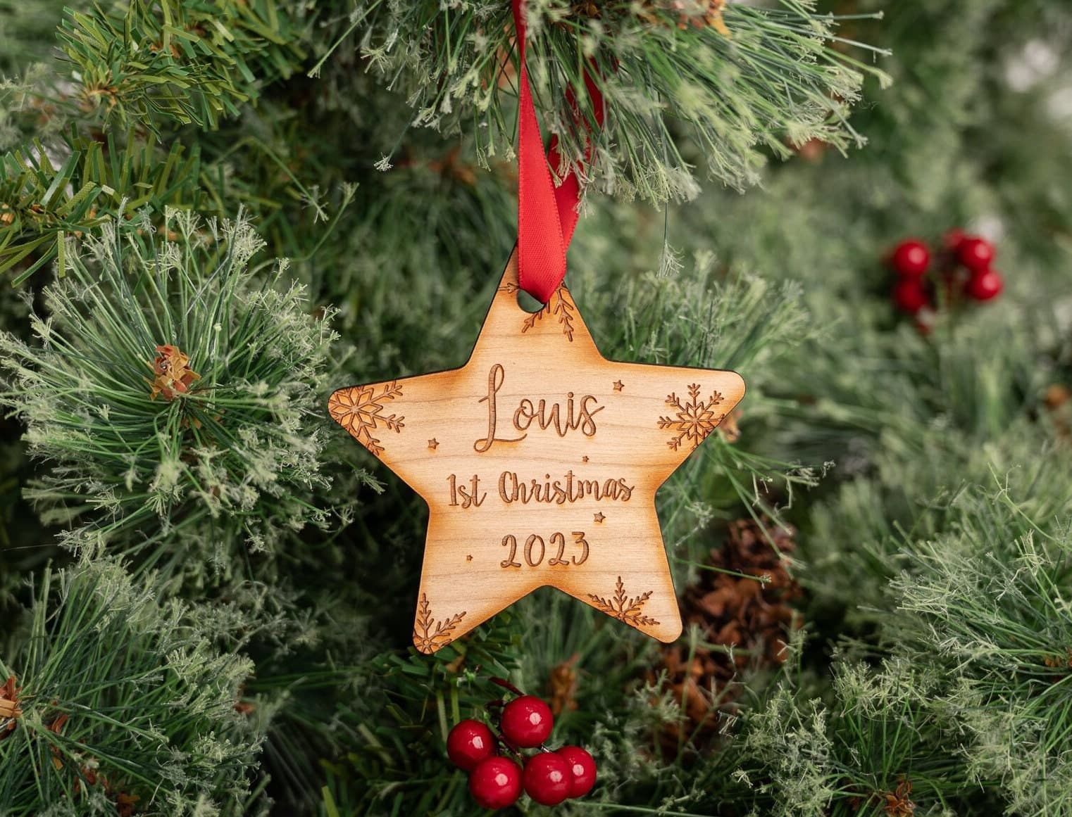 wooden star shaped bauble with snowflakes engraved on the background with the words louis 1st christmas 2023 on