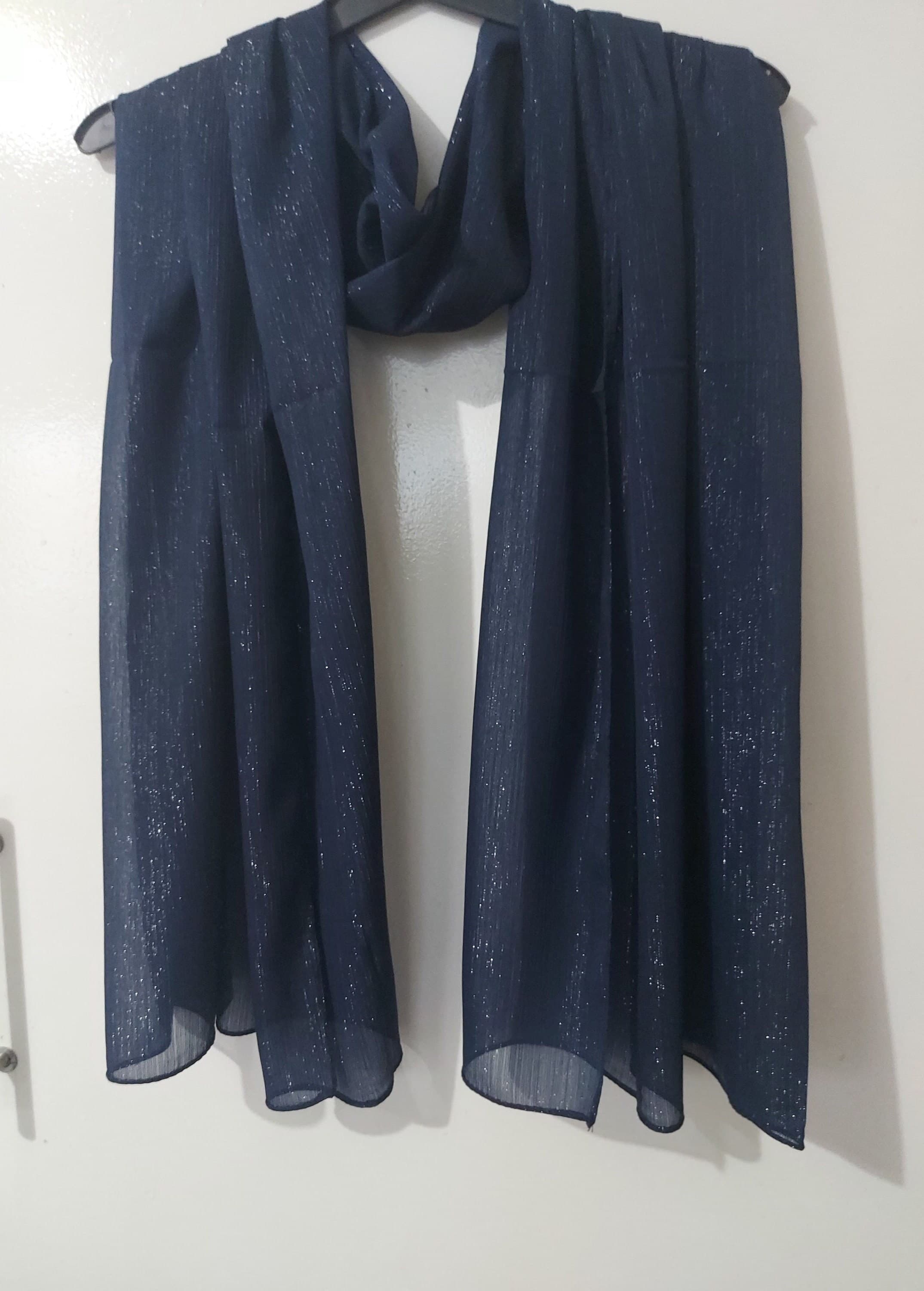 May include: A navy blue sheer scarf with silver glitter throughout. The scarf is draped over a hanger.