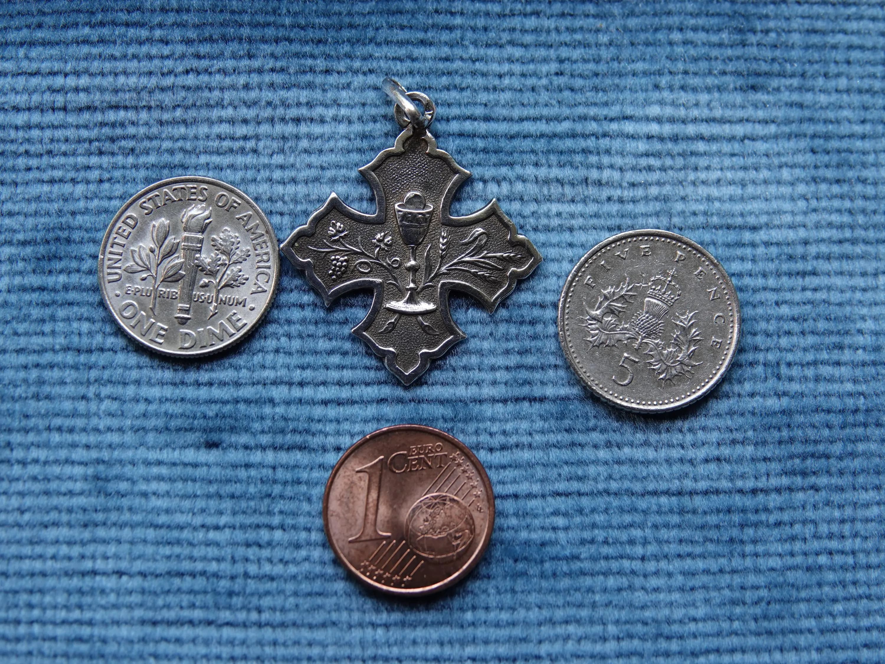 Art nouveau silver Eucharist medal in the shape of a Cross with three coins for scale