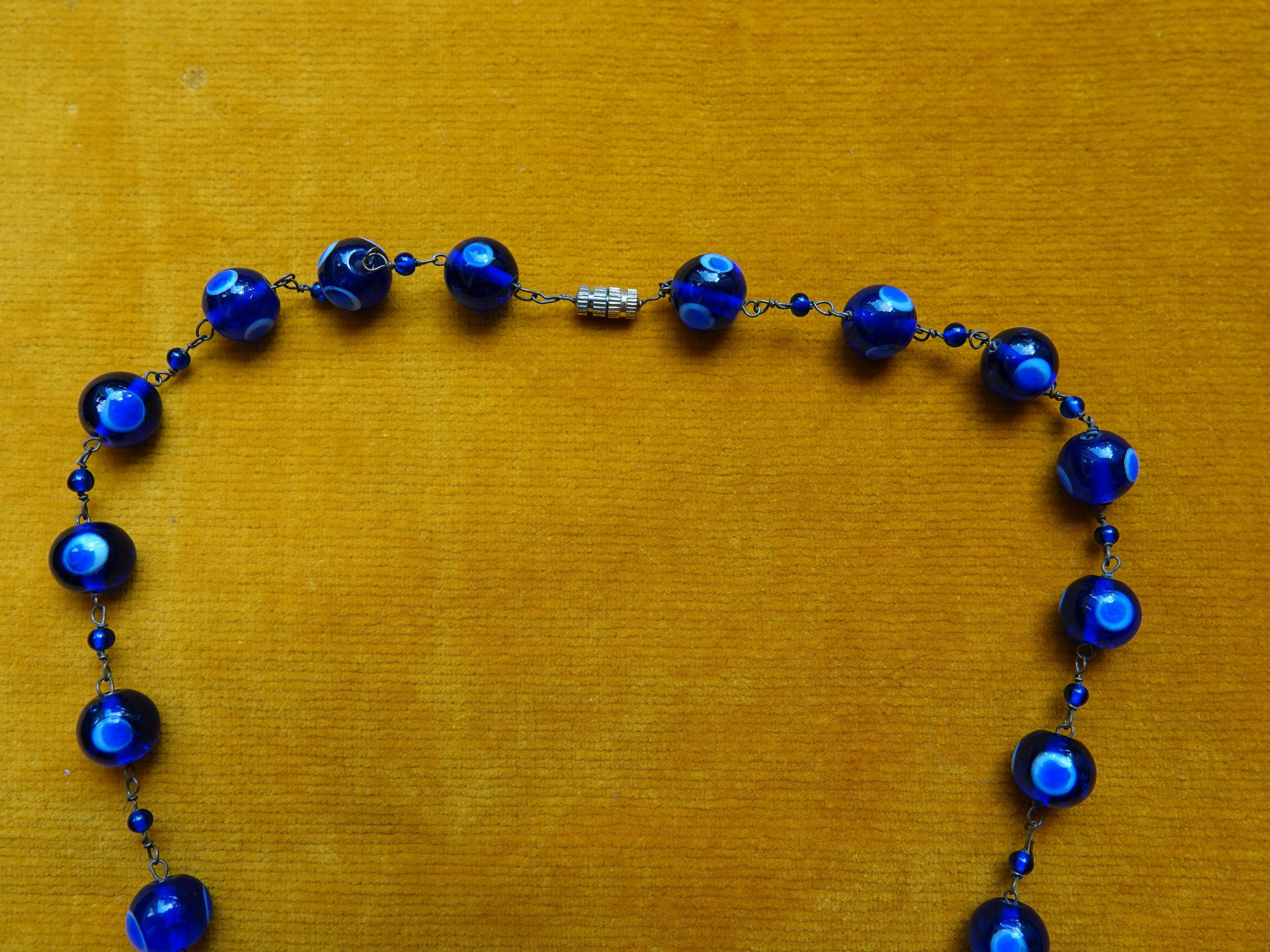 Detail of beads on vintage Cobalt blue necklace with thousand eyes design. The links are brass chain with tiny cobalt blue spacers. The necklace fastens with a brass barrel fastener