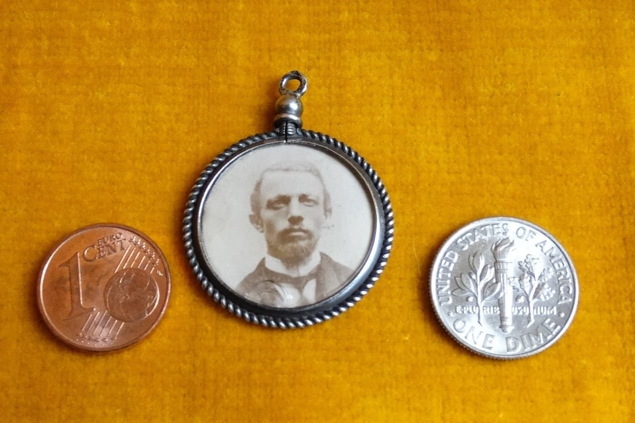 Antique silver photo pendant with small coins for scale