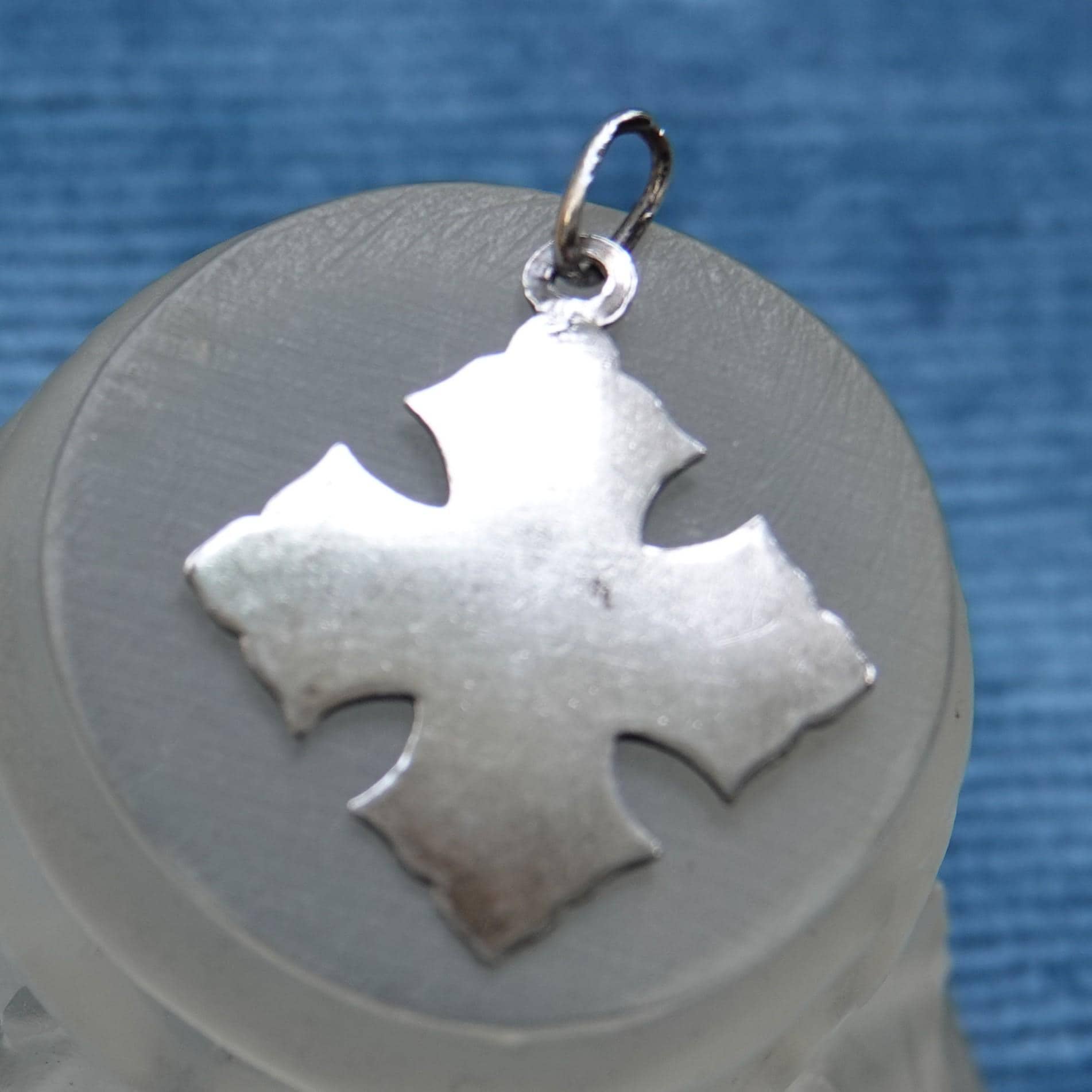 Back of silver Eucharist charm, which is blank