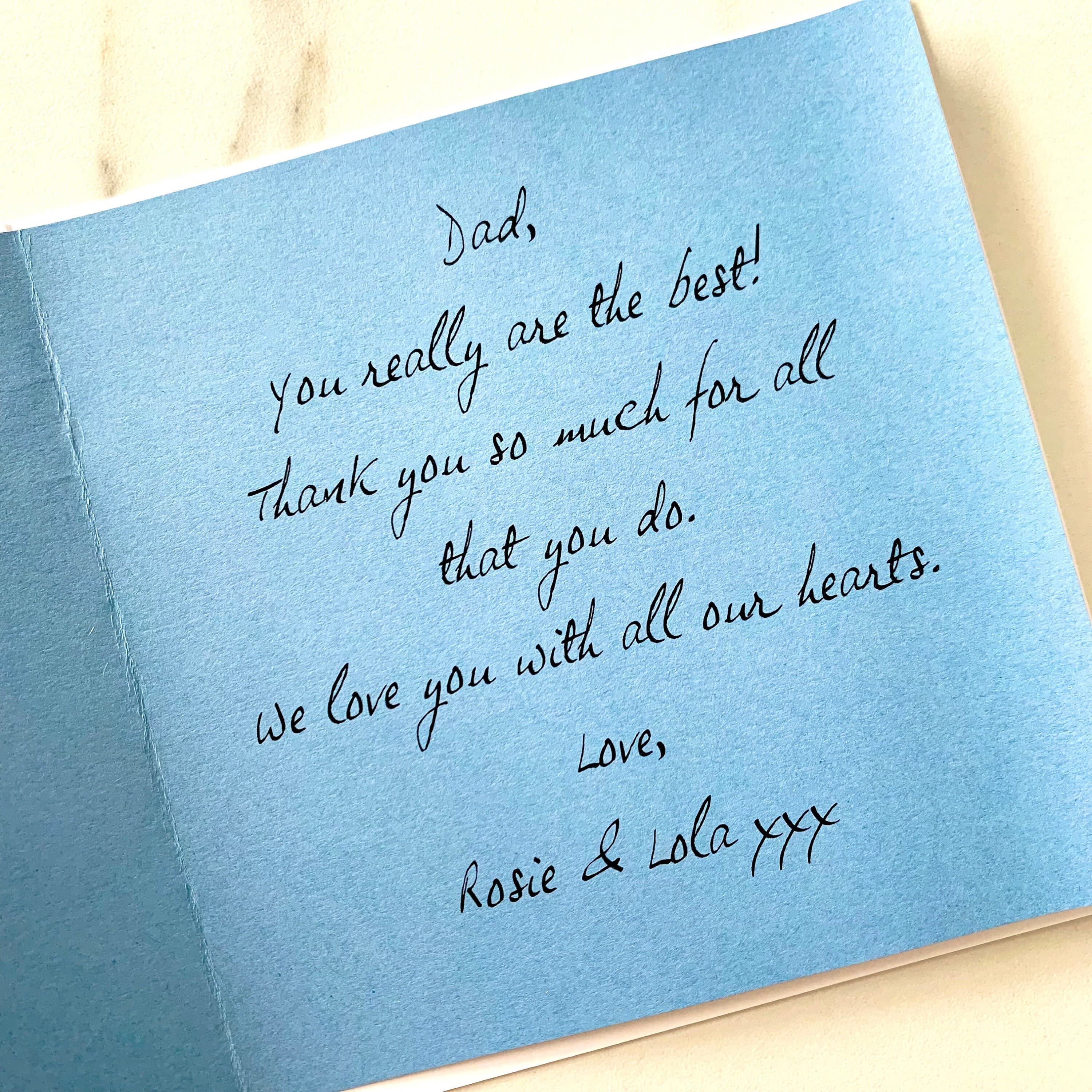 Close up of a pale blue insert inside a card, printed with a message wishing a Happy Father’s Day in a handwritten-style font.