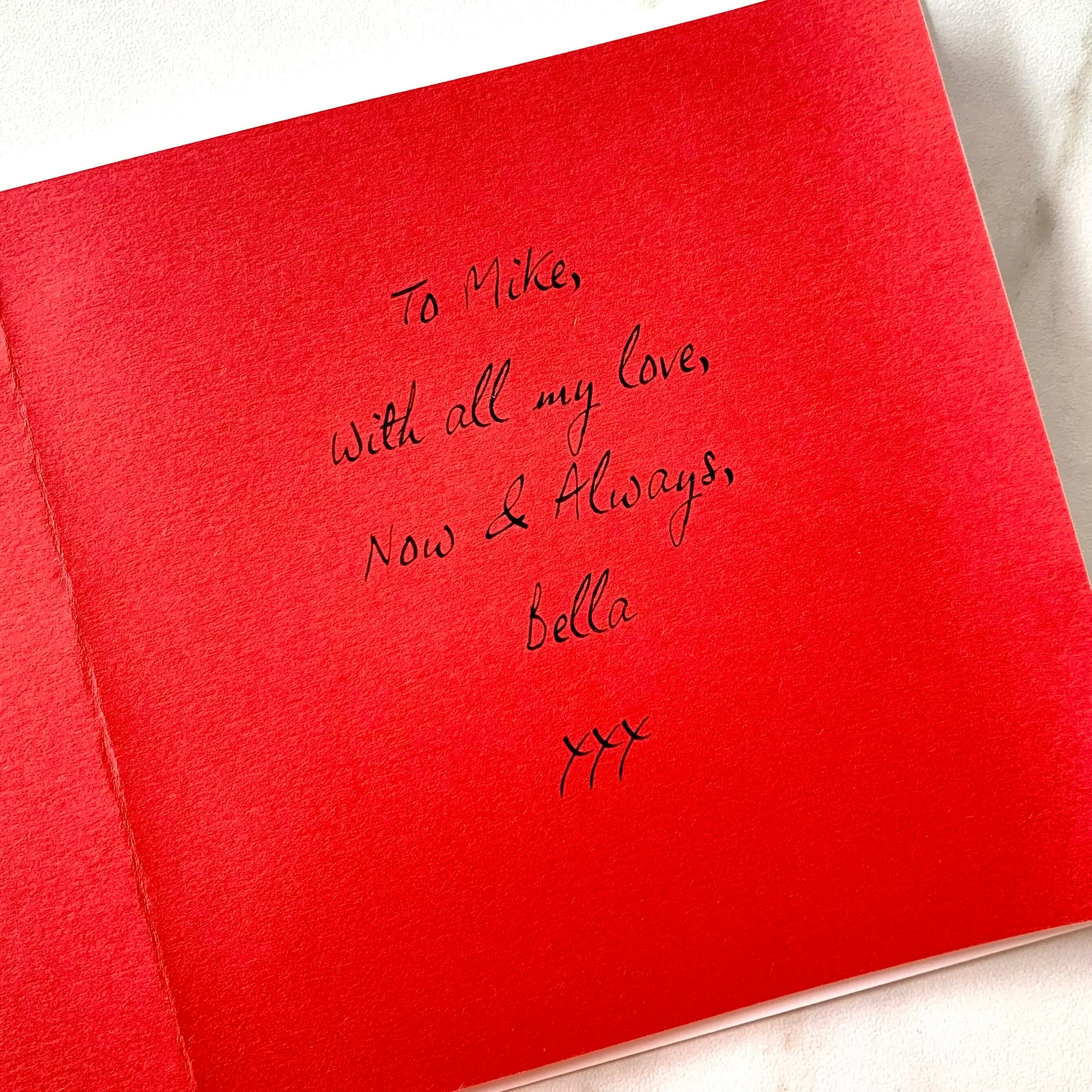 Close up of a bright red paper insert inside a card, printed with a message sending love to the recipient in a handwritten-style font.
