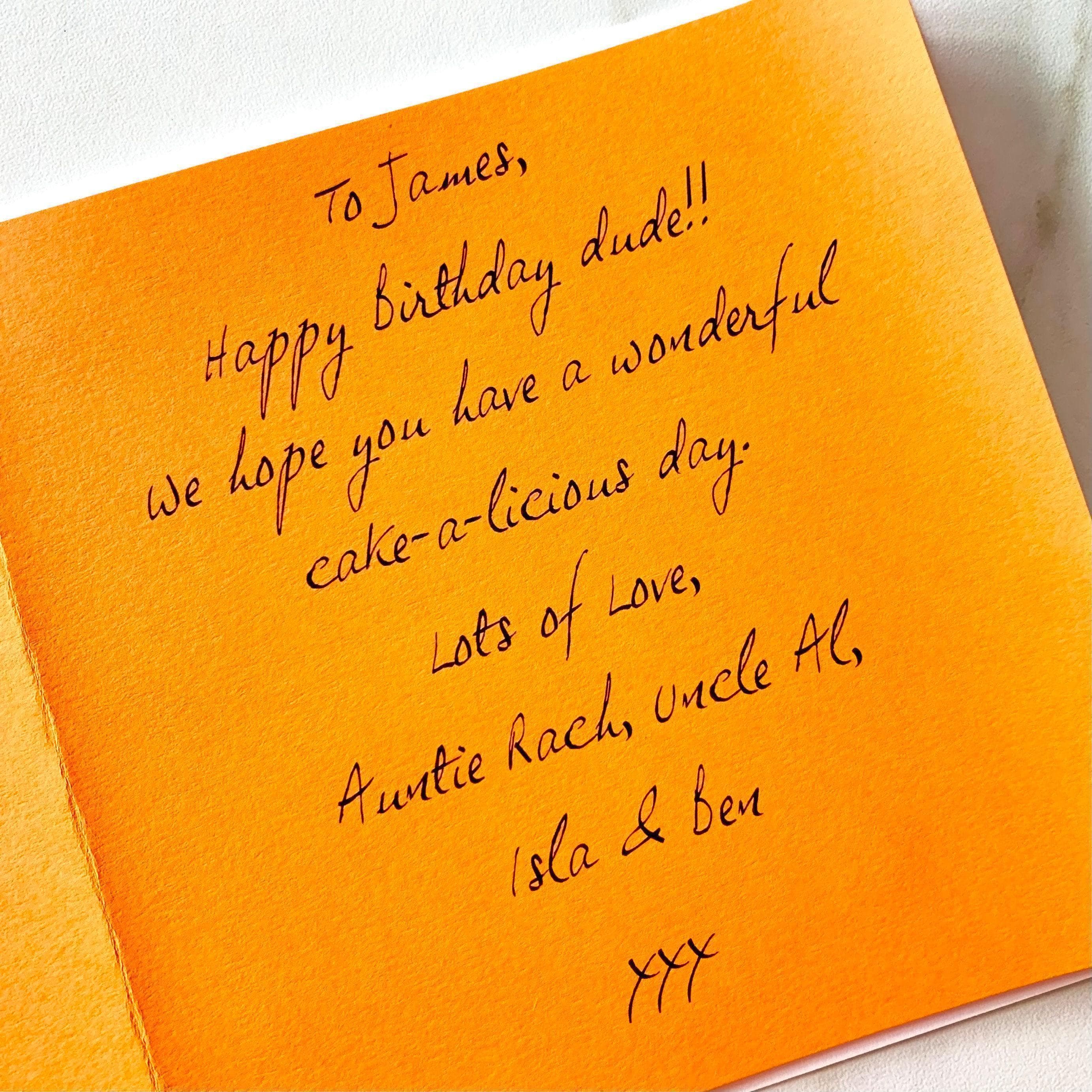 Close up of a bright orange paper insert inside a card, printed with a message wishing a happy birthday in a handwritten-style font.