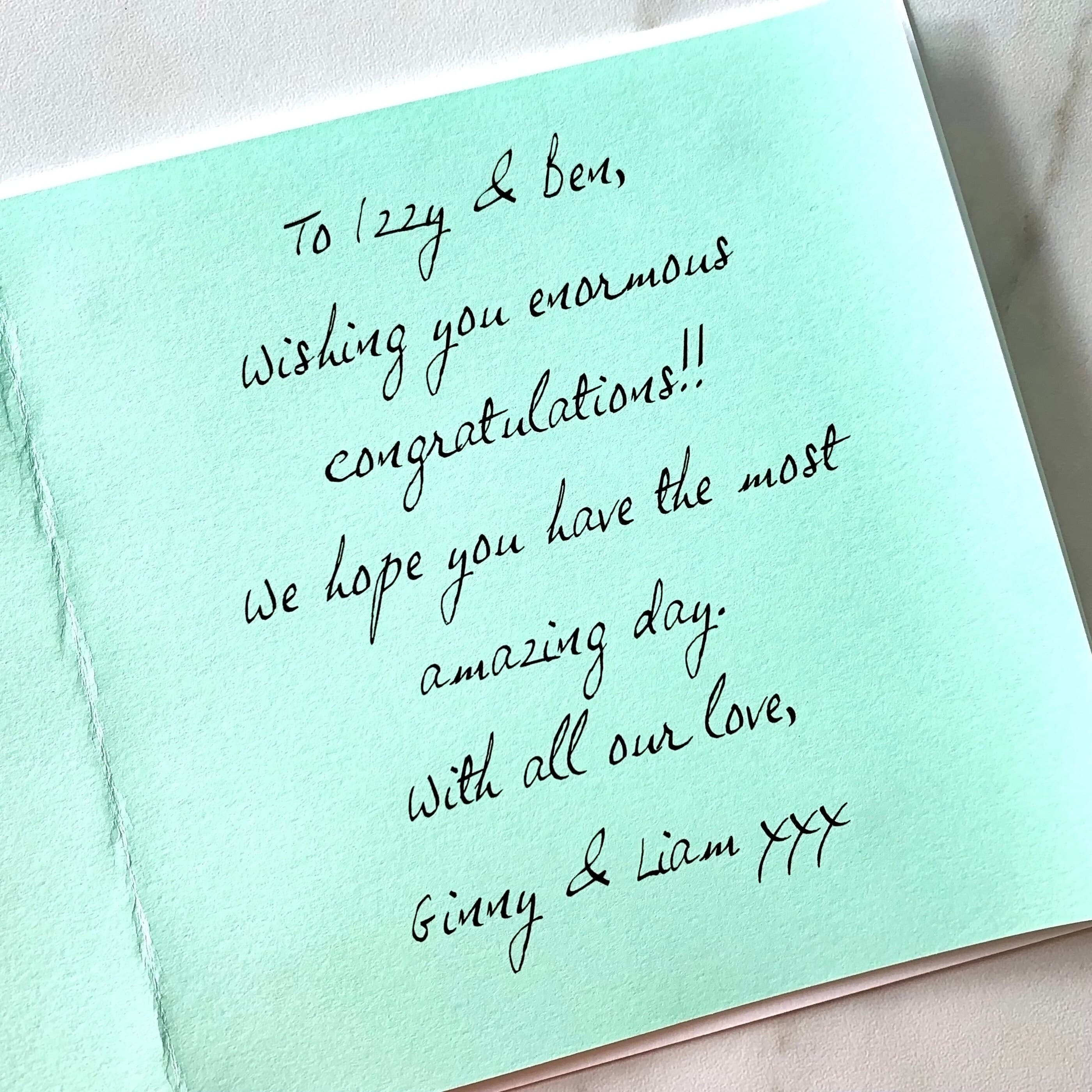 Close up of a mint green paper insert inside a card, printed with a message wishing congratulations to the recipients in a handwritten-style font.