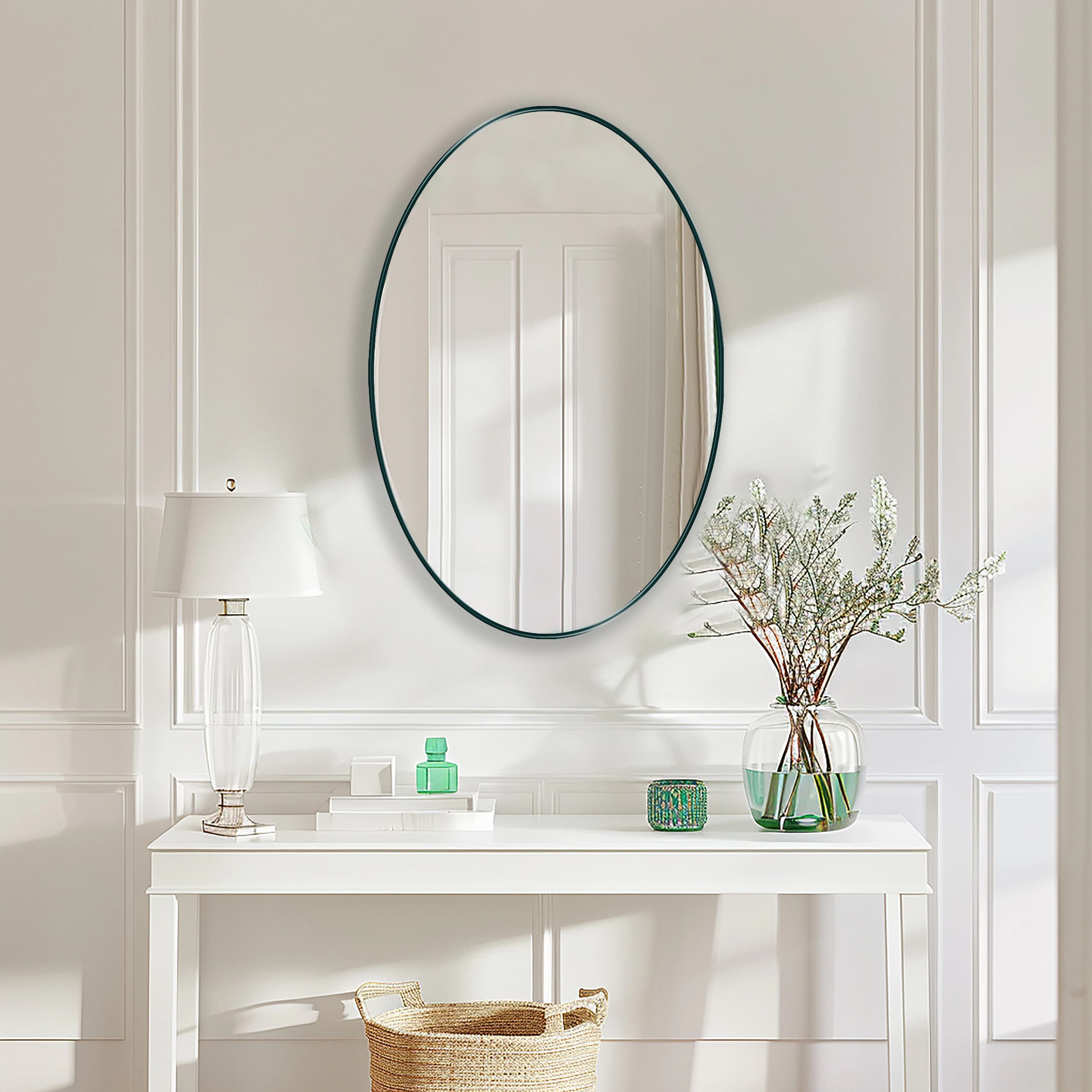 Oval Mirror with emerald frame hung on the wall of an entryway over a console.