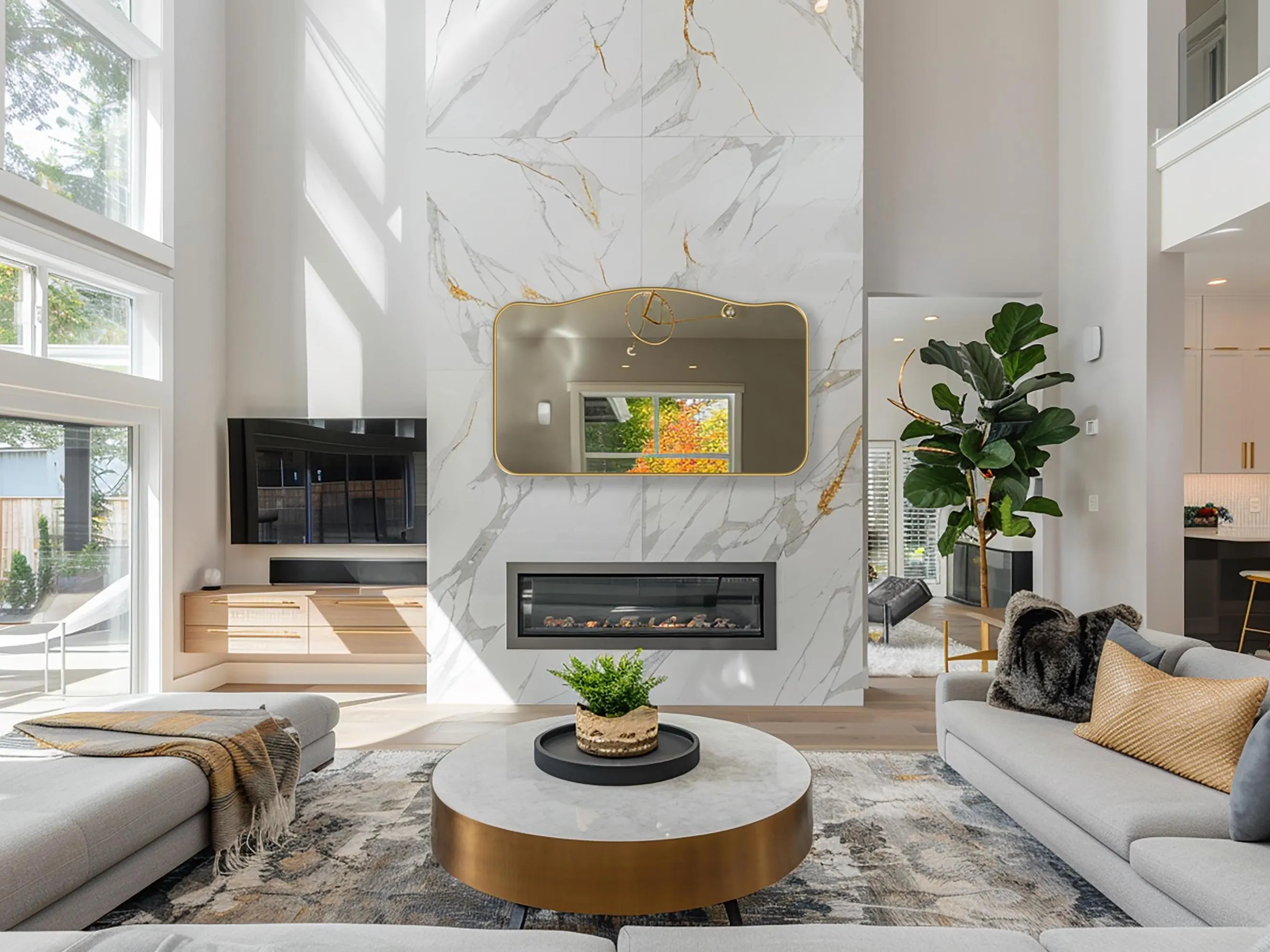 Alpine Mirror with gold frame finish hung on the wall of a living room over a fireplace.
