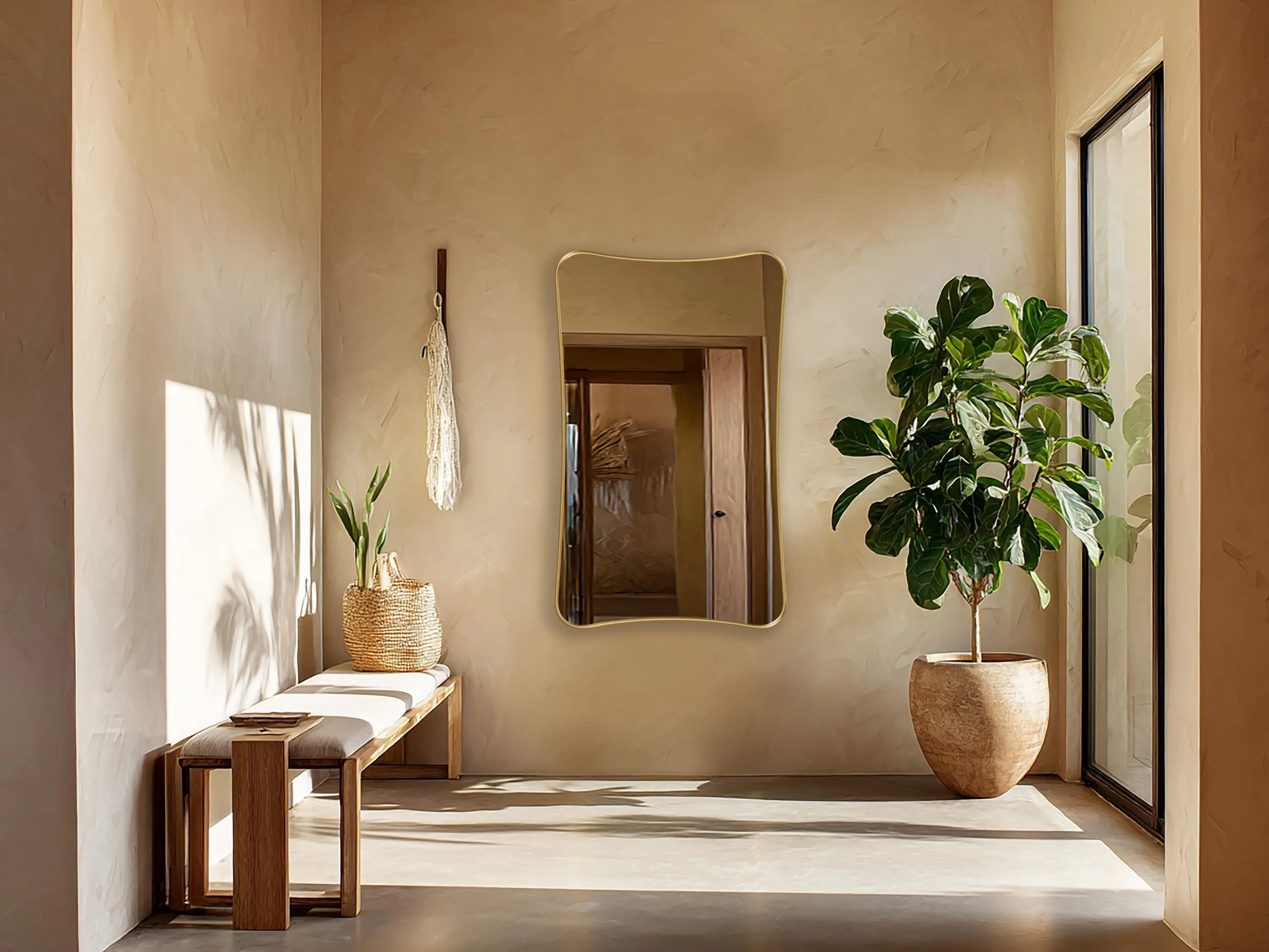 Talisman Mirror with gold frame finish hung on the wall of an entryway.