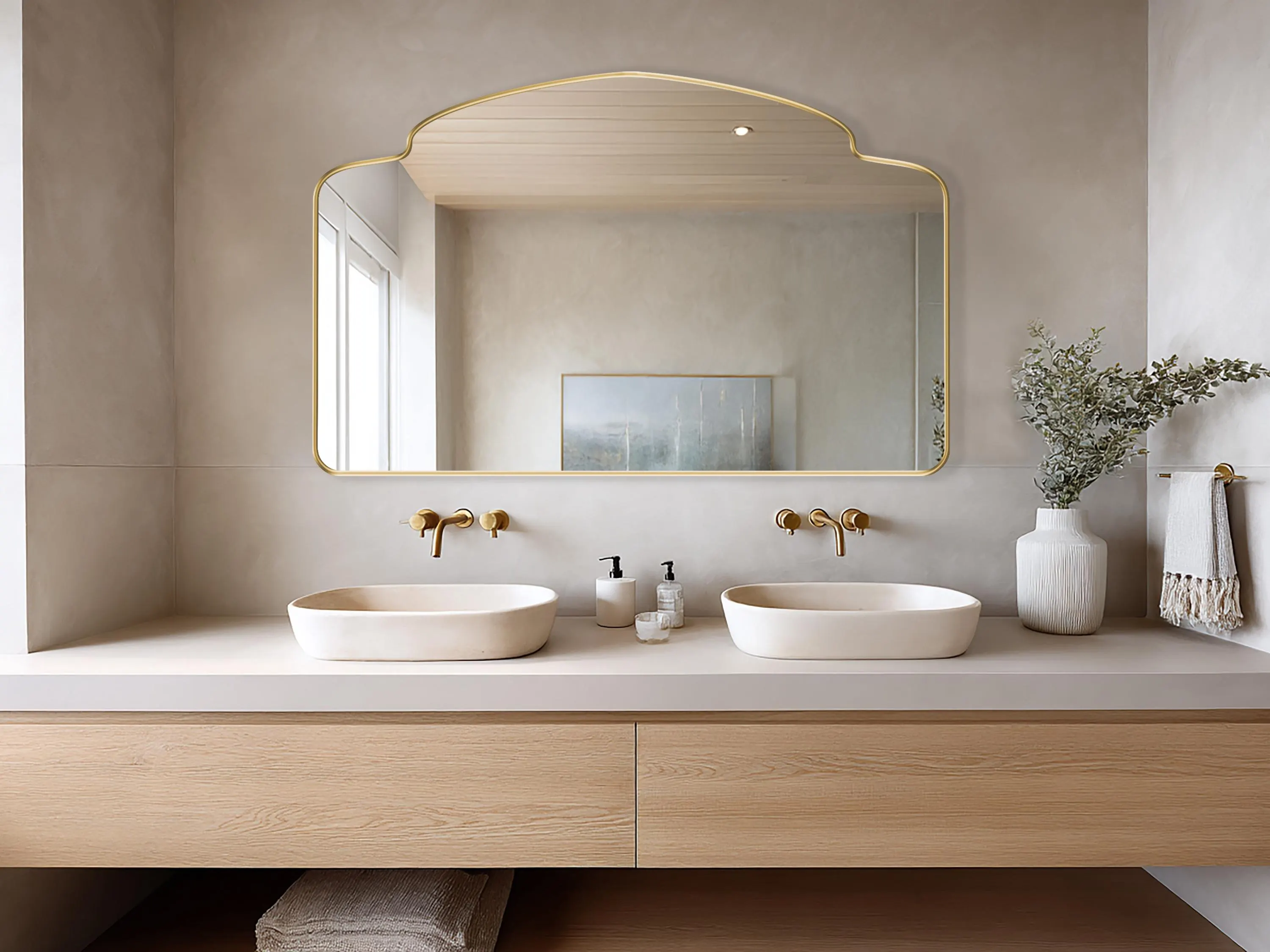 Alhambra Mirror with gold frame finish hung on the wall of a bathroom over a double vanity.