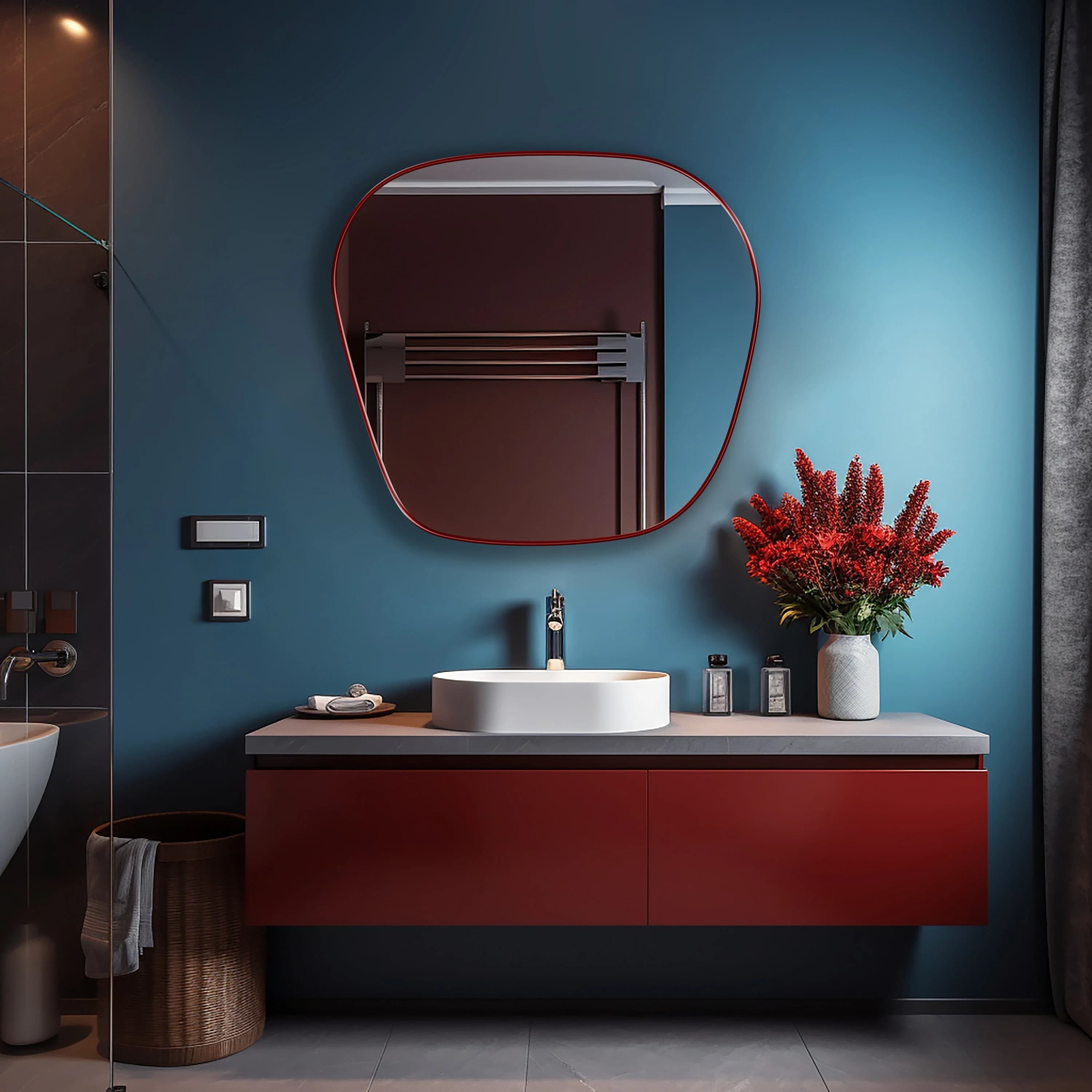 Blob mirror with red frame finish hung on the wall of a bathroom over a vanity.