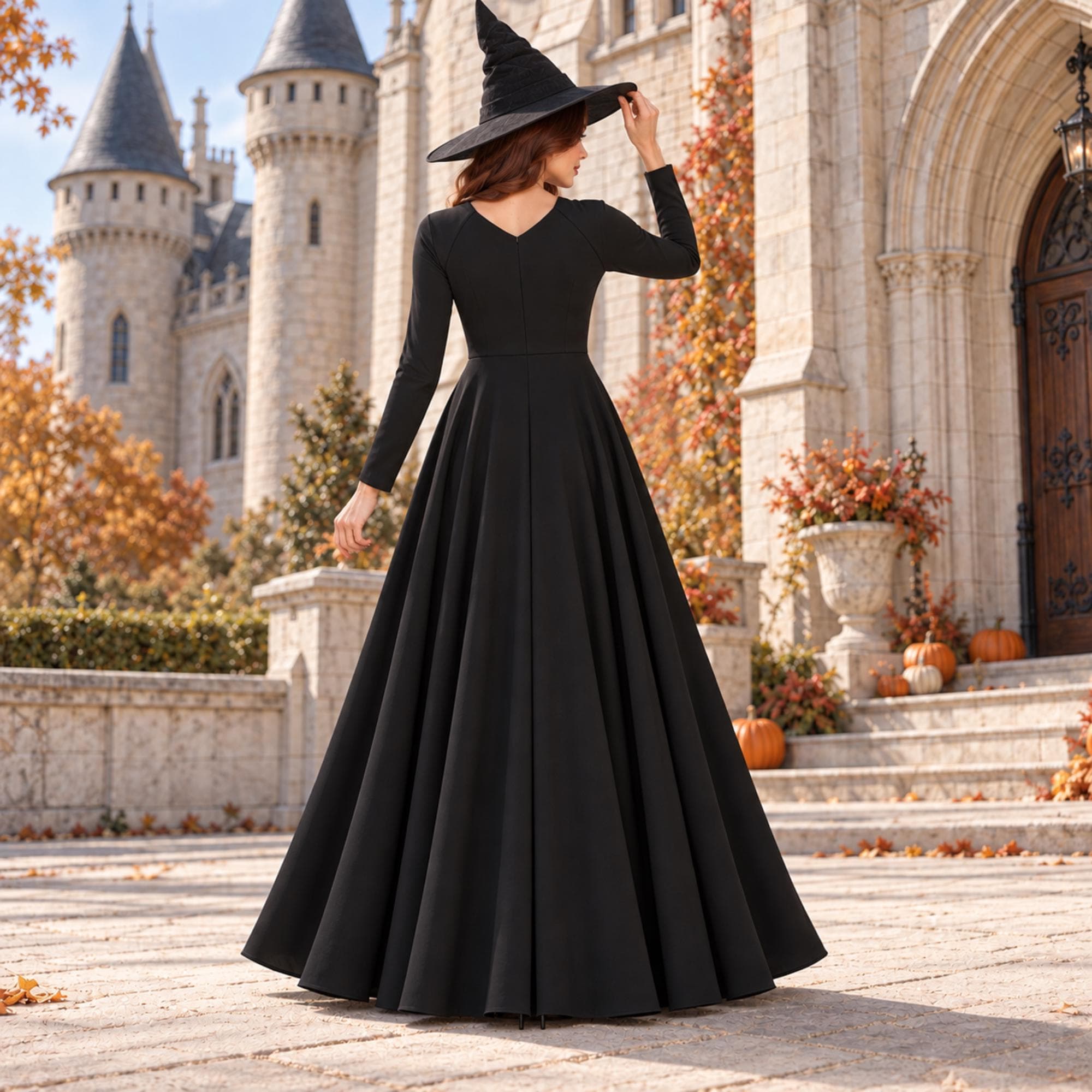 Black gothic high-low dress sewing pattern with V neckline and long sleeves styled as a Halloween witch outfit in a castle setting.