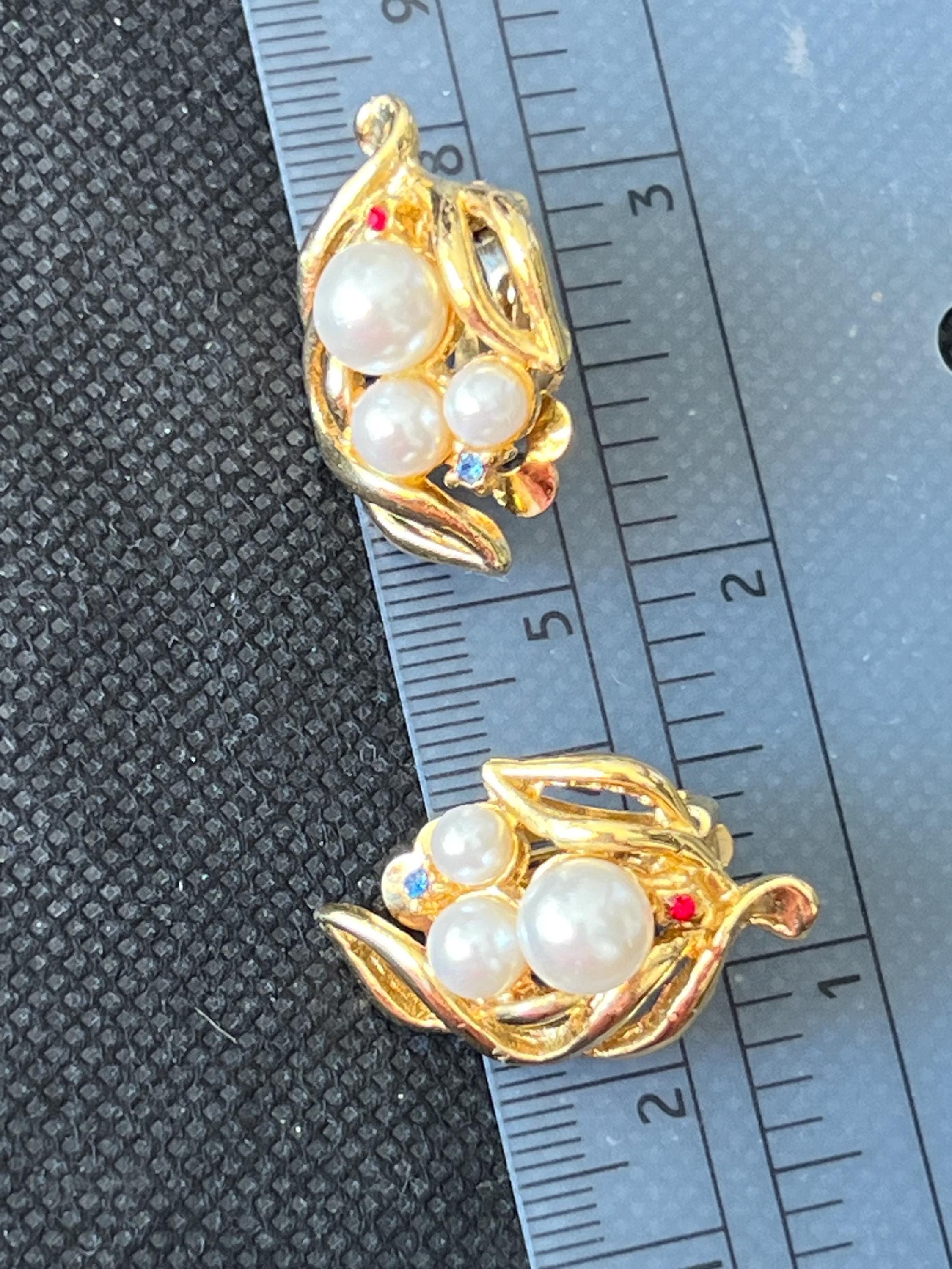 Vintage gold-tone clip-on earrings with floral design and imitation pearls on a ruler